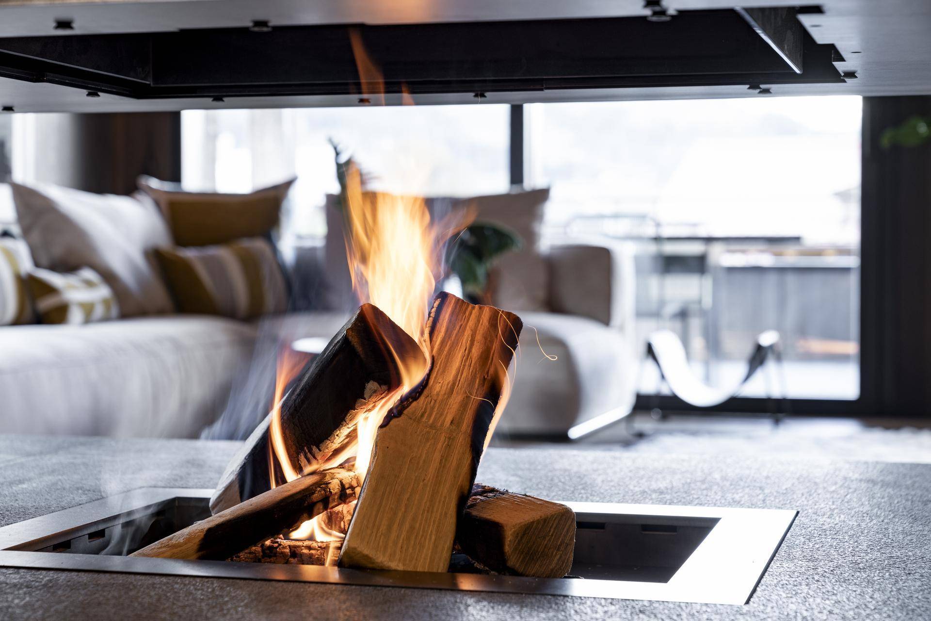 Moderner Kamin mit Holzscheiten, der eine warme Atmosphäre im Wohnbereich schafft.