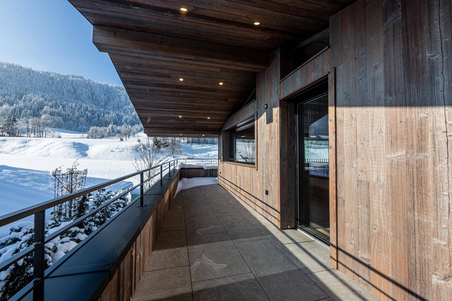 Langer Balkon mit Holzverkleidung und weitem Blick auf die winterliche Landschaft.