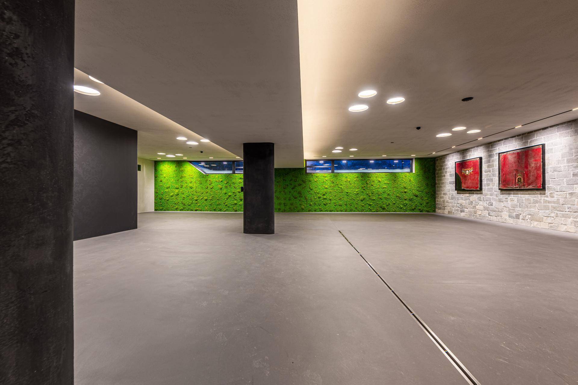Weitläufige Tiefgarage mit Mooswand-Dekoration, Steinwand und indirekter Beleuchtung für eine besondere Atmosphäre.