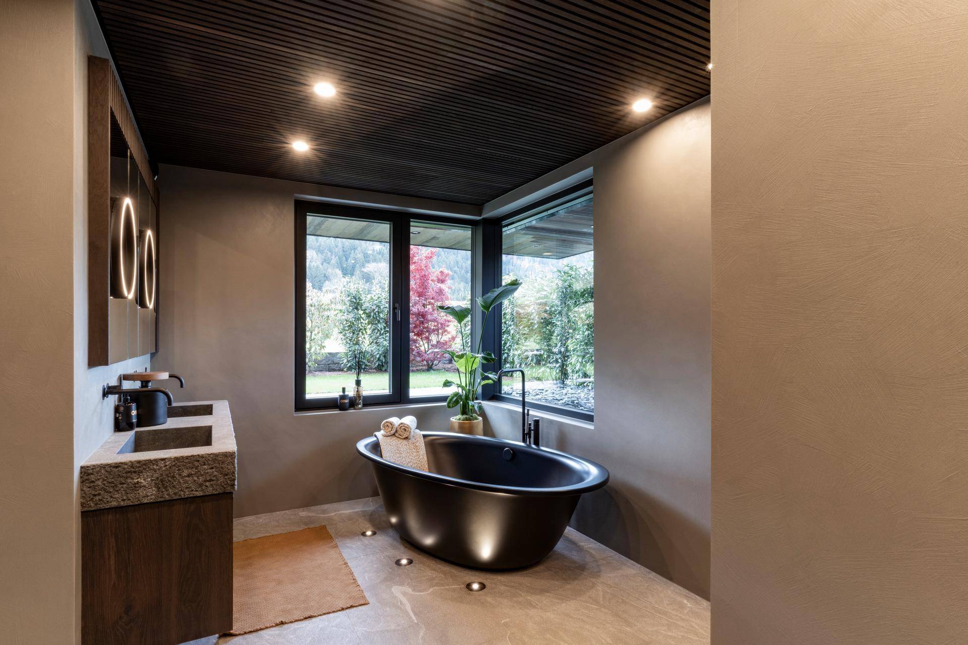 Luxuriöses Badezimmer mit freistehender Badewanne, Doppelwaschbecken und Fensterblick.
