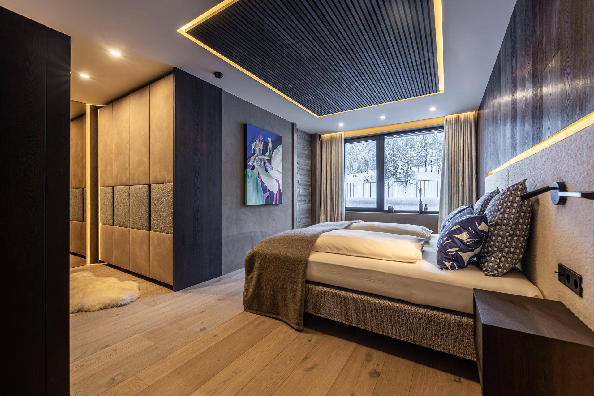 Modernes Schlafzimmer mit Holzboden, Einbauschränken und indirekter Deckenbeleuchtung für gemütliche Atmosphäre.