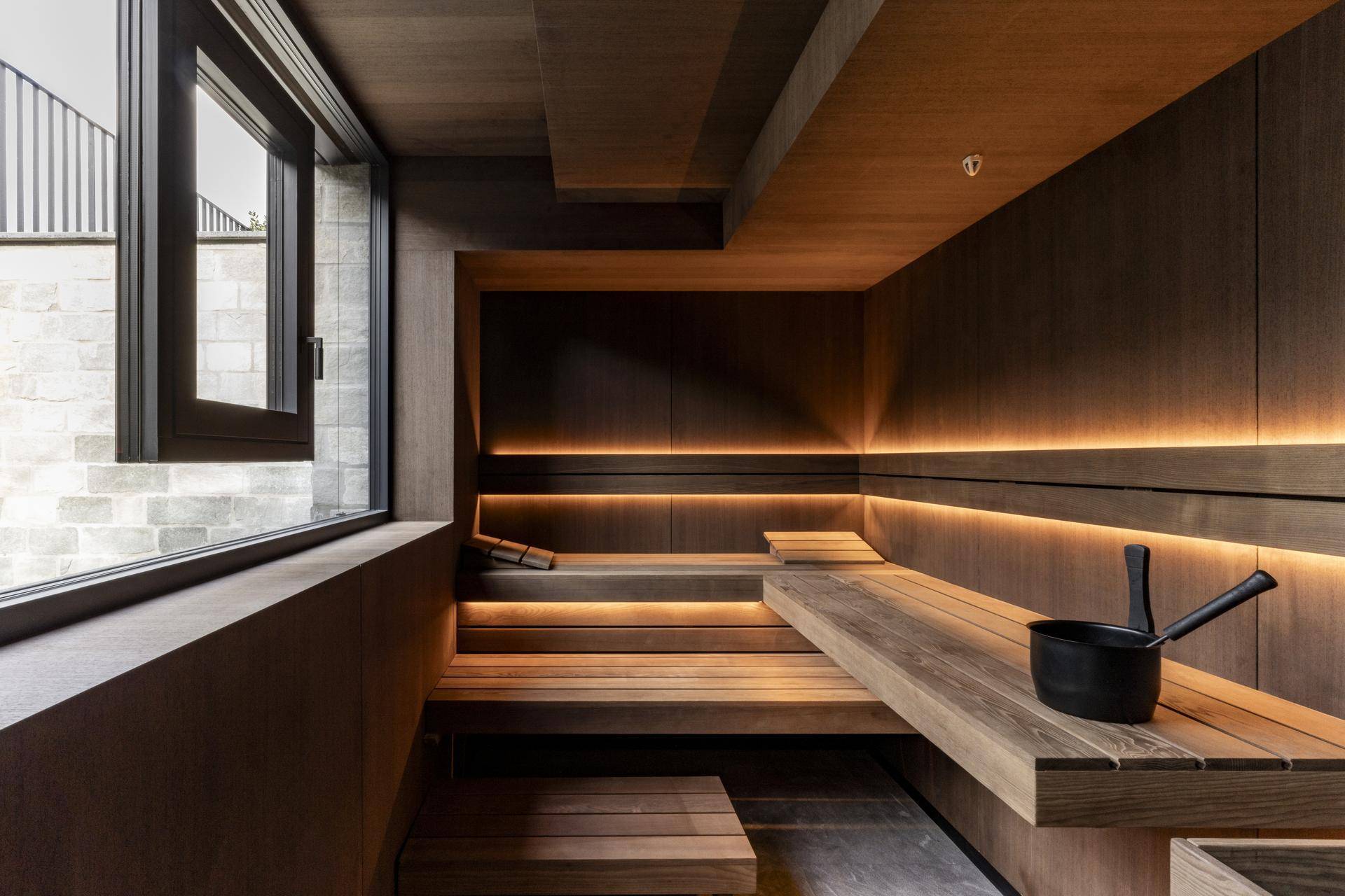 Moderne Sauna mit Holzverkleidung, mehrstufigen Bänken und indirekter Beleuchtung.