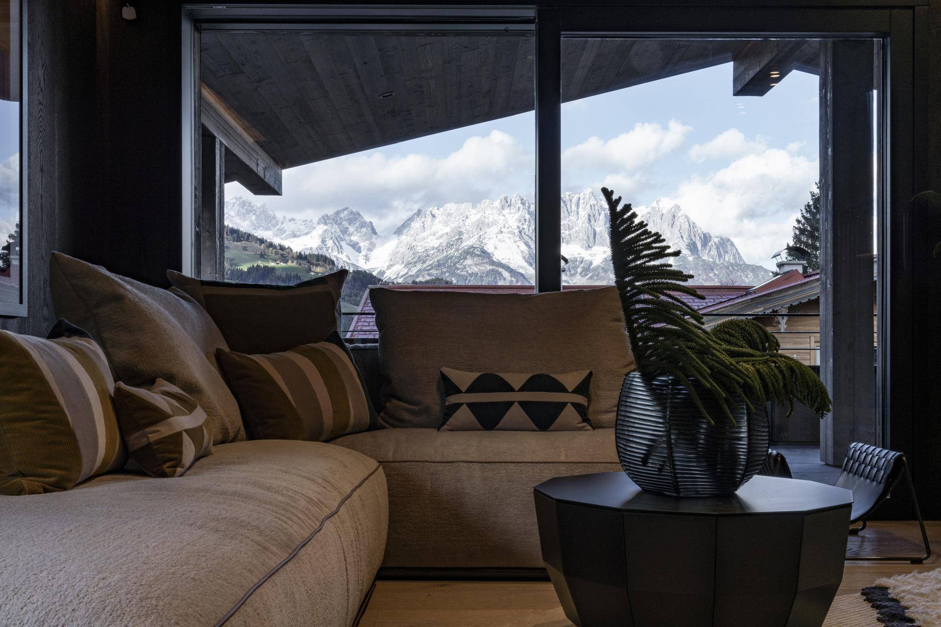 Wohnzimmer mit bequemer Couch, Couchtisch und atemberaubendem Blick auf die Berge.