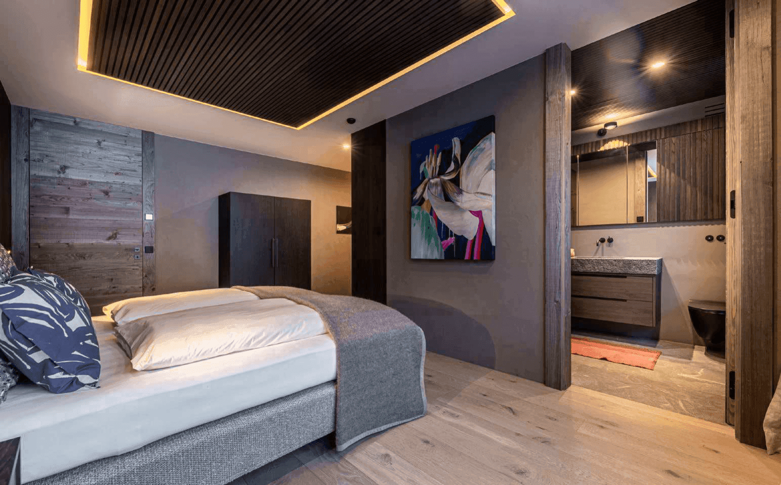 Schlafzimmer mit Holzboden und offenem Zugang zu einem modernen Ensuite-Badezimmer.