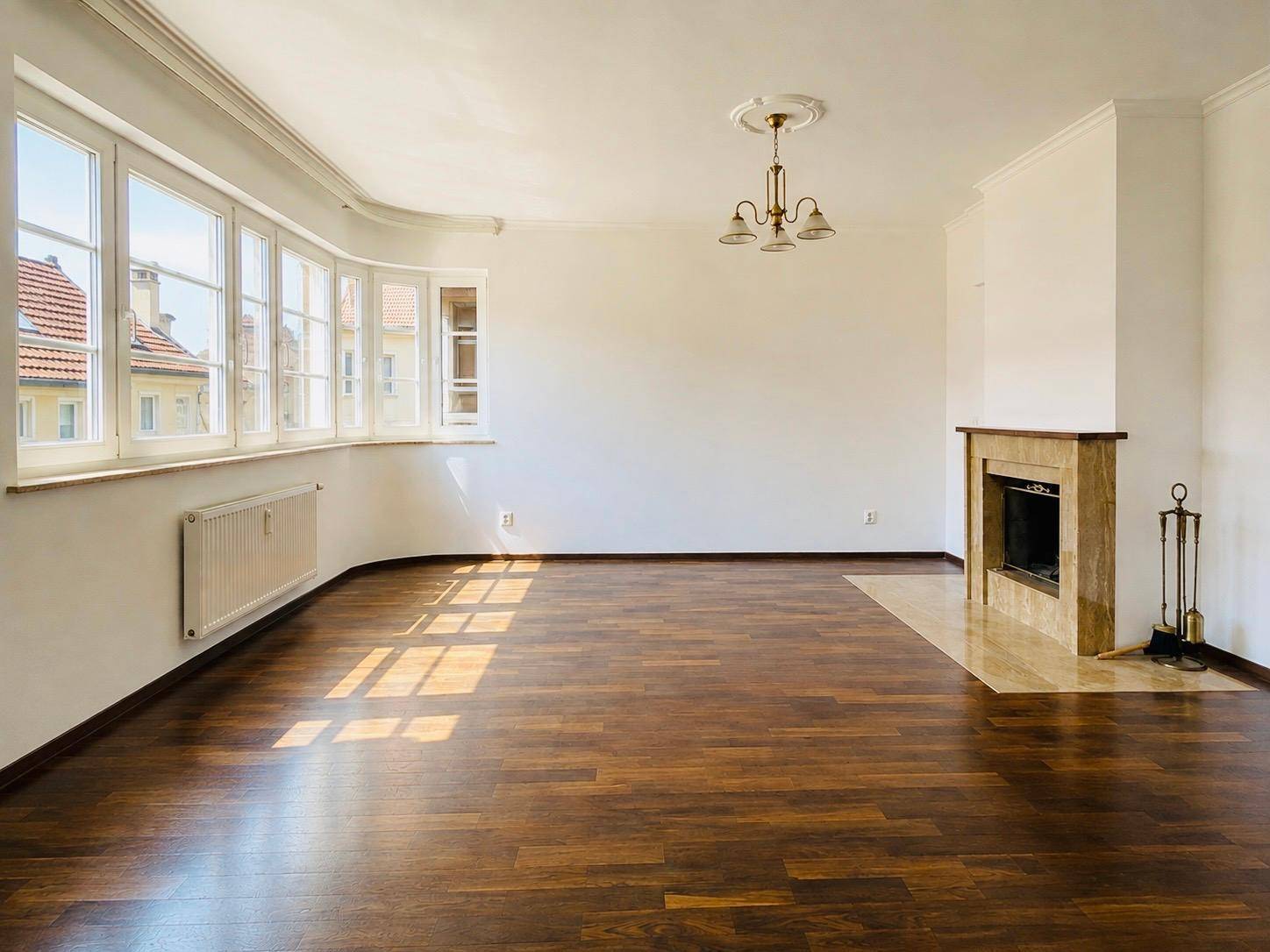 Helles Wohnzimmer mit Holzboden, Erkerfenstern und einem eleganten Kamin.
