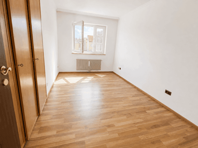 Leeres Schlafzimmer mit Holzboden, Fenster und Einbauschränken, hell und geräumig.