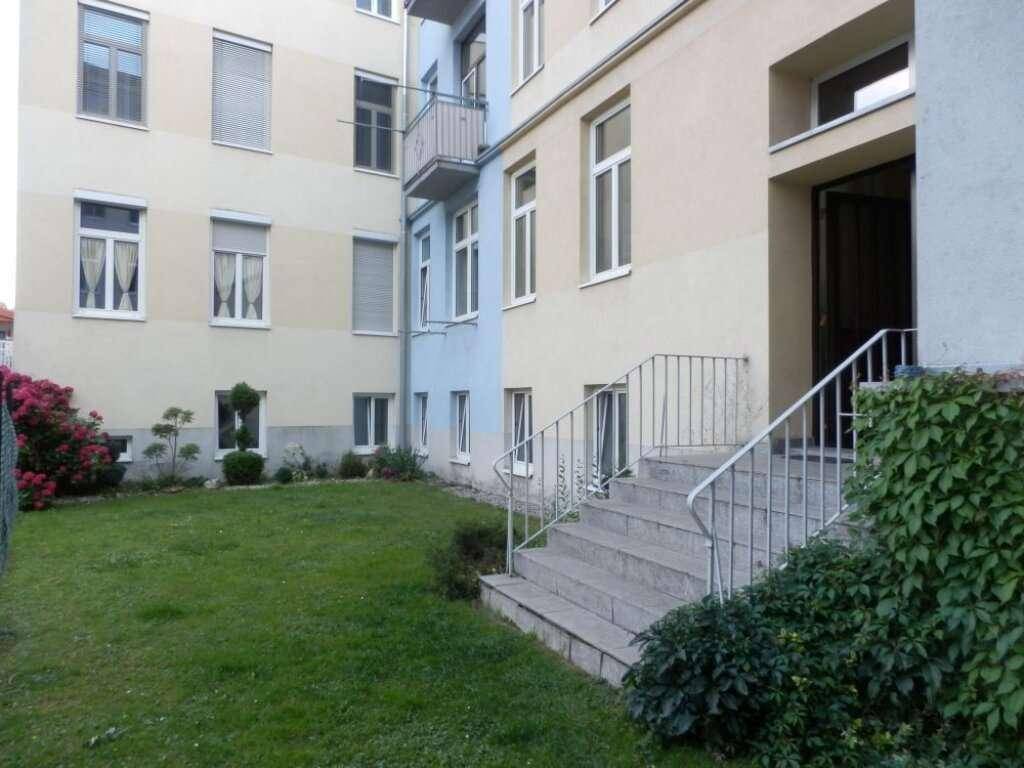 Außenansicht eines Mehrfamilienhauses mit gepflegtem Vorgarten und Balkonen.