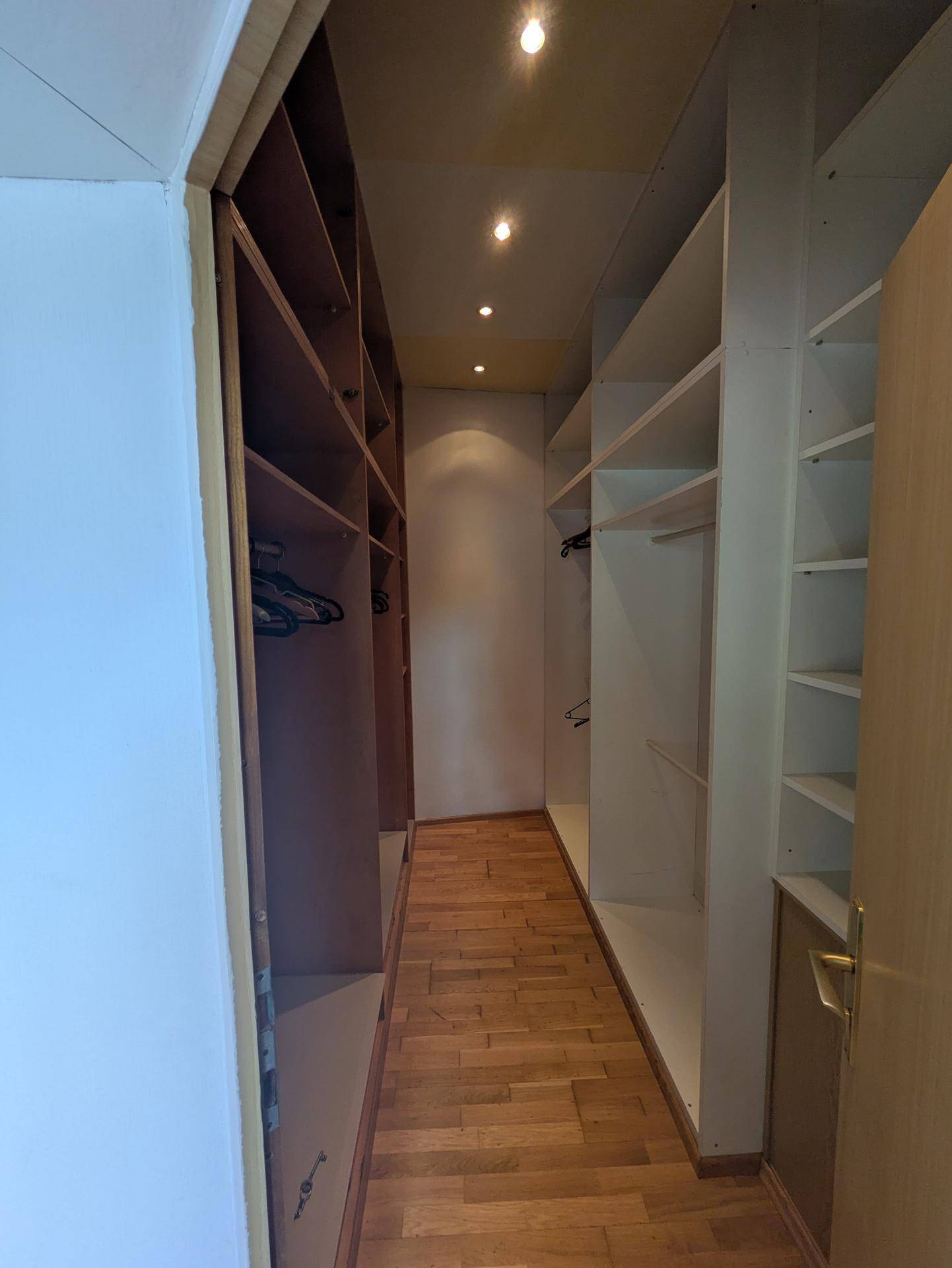 Geräumiger begehbarer Kleiderschrank mit vielen Regalen und integrierter Beleuchtung für optimale Organisation.