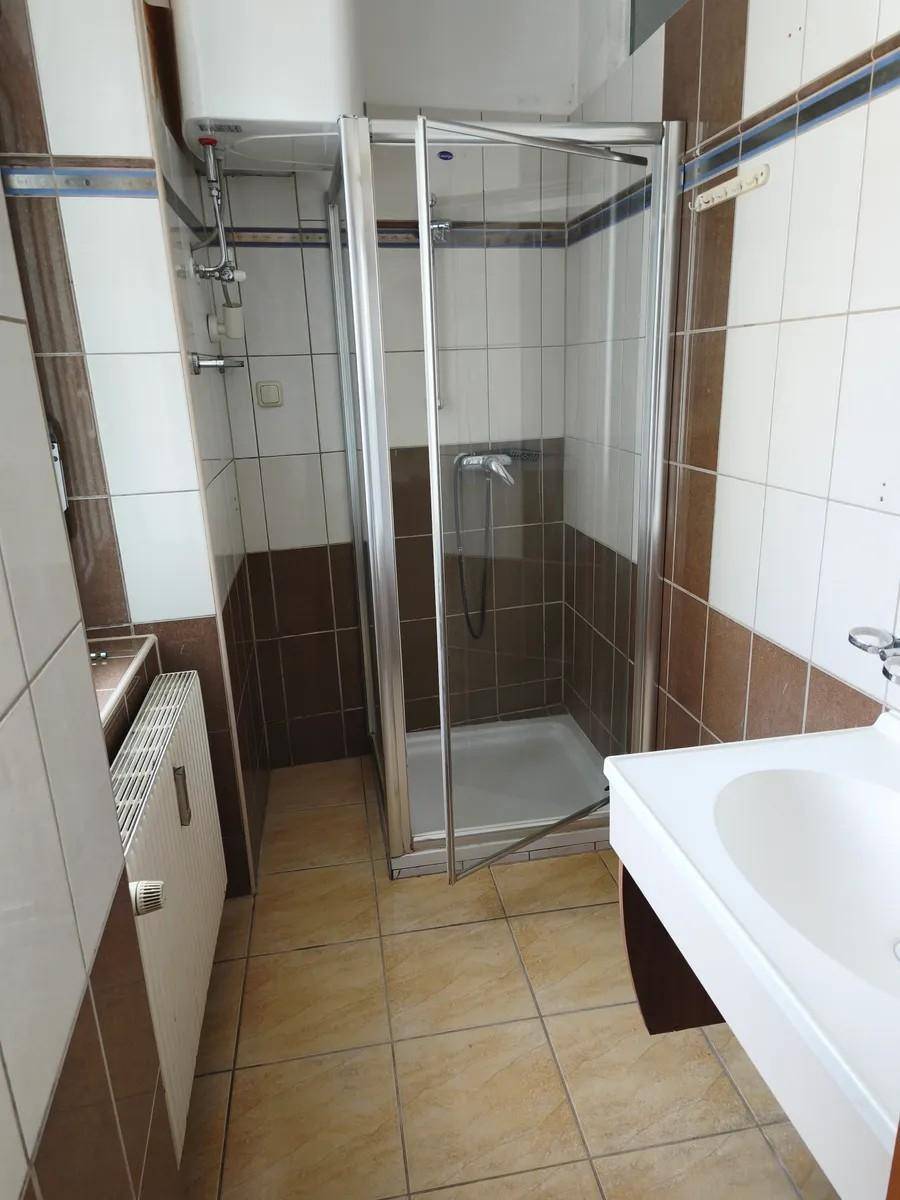 Badezimmer mit Duschkabine, Waschbecken und Fliesen in Braun- und Beigetönen.