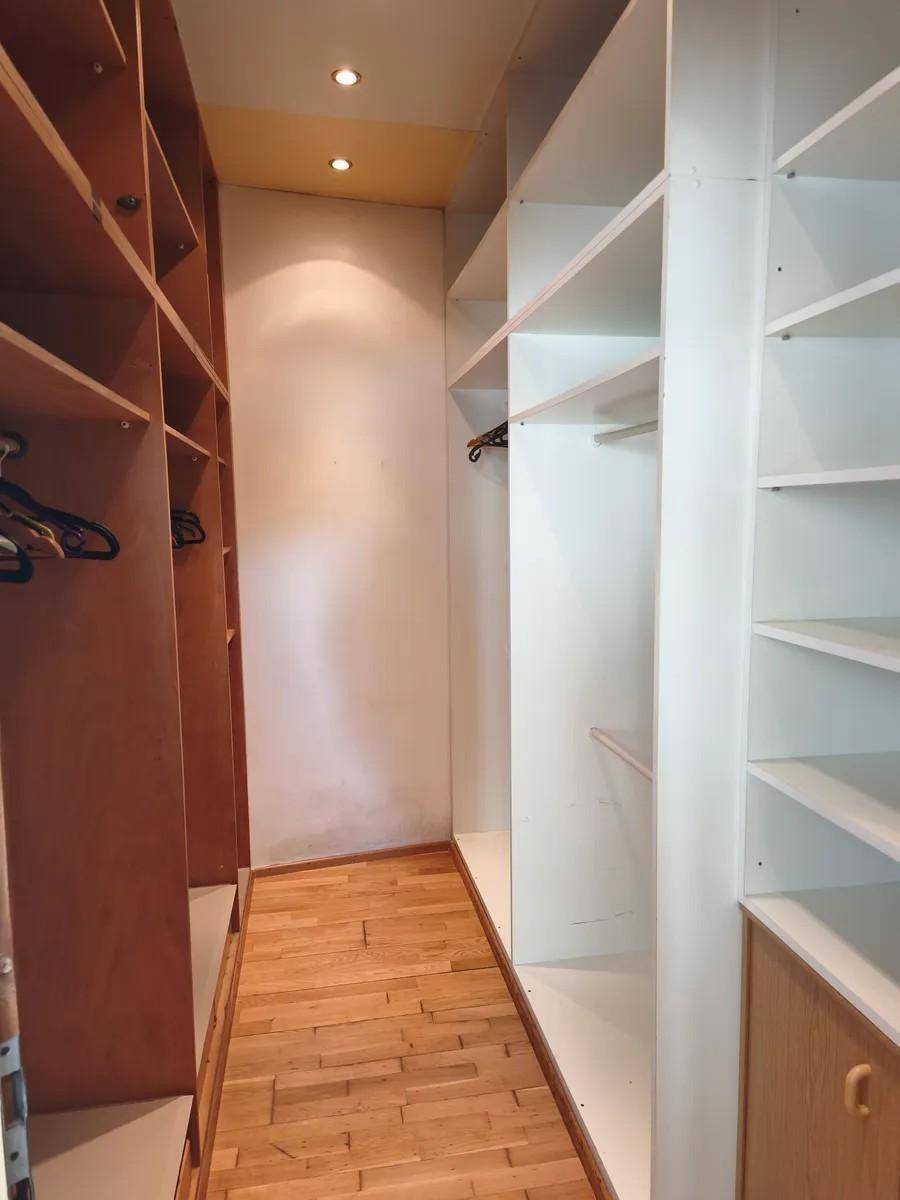 Geräumiger begehbarer Kleiderschrank mit maßgefertigten Regalen und Holzboden.