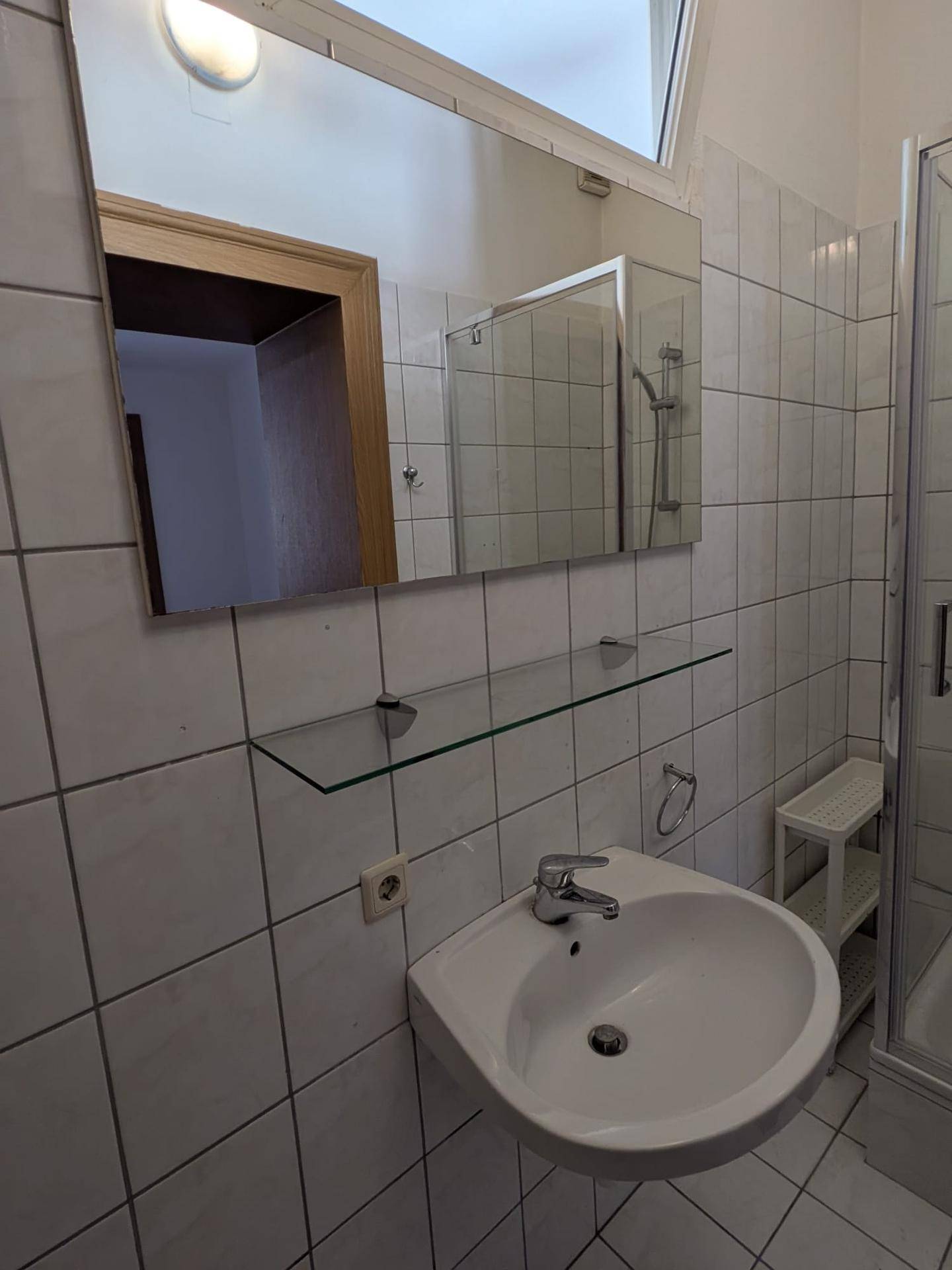 Badezimmer mit Waschbecken, großem Spiegel und Duschkabine, das eine helle und saubere Umgebung bietet.