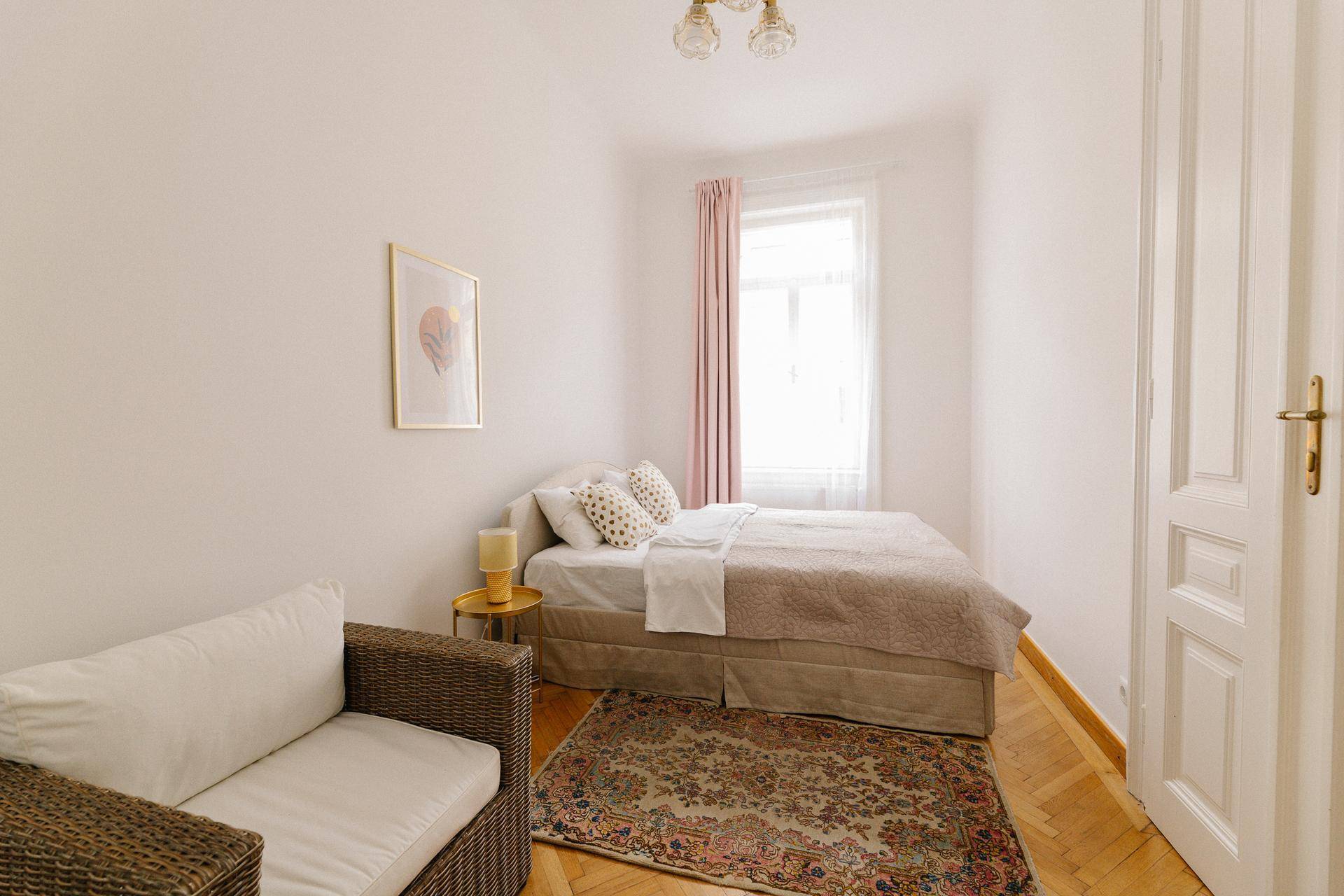 Gemütliches Schlafzimmer mit Doppelbett, Teppich und Fenster mit rosa Vorhängen.