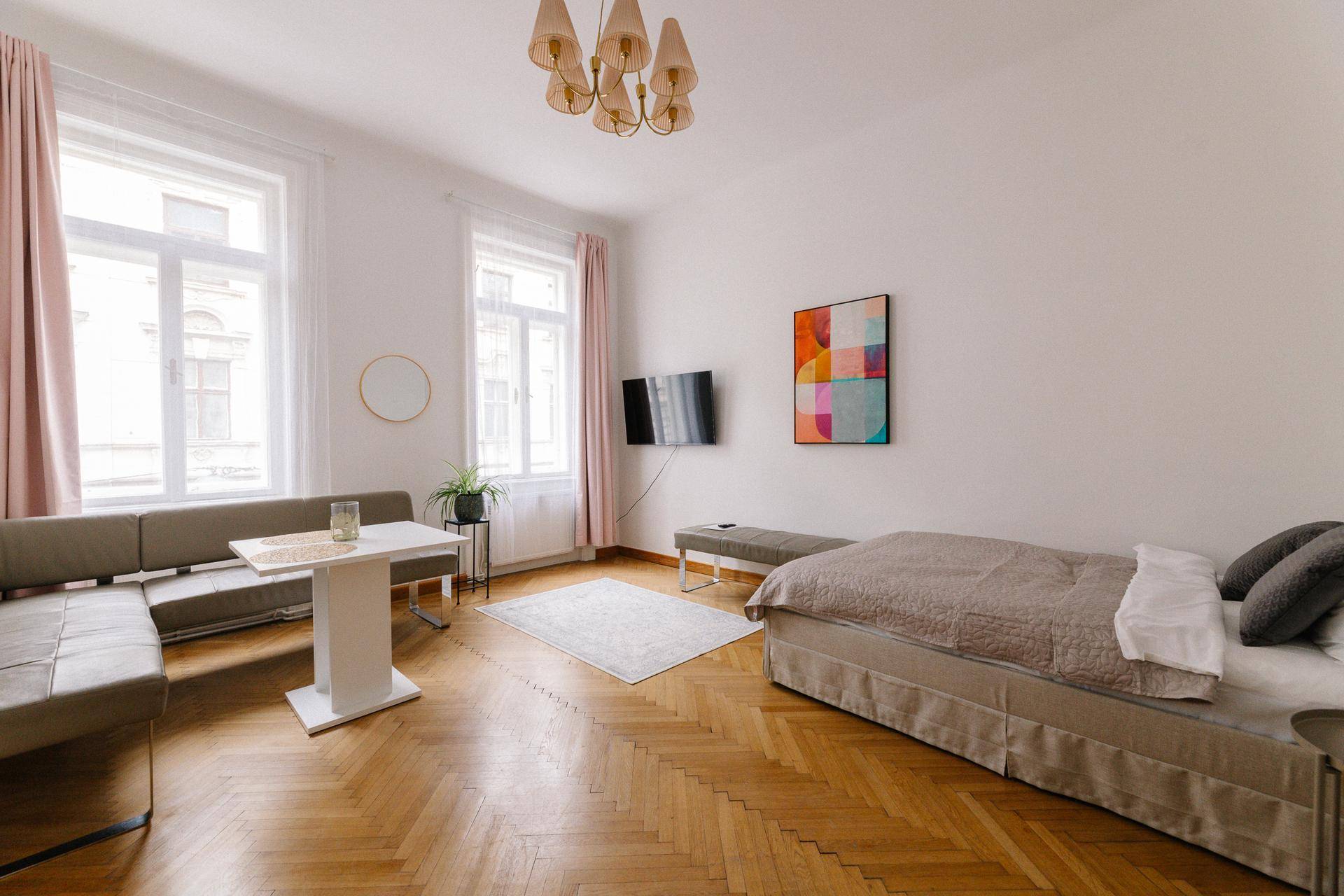 Heller Wohnbereich mit Parkettboden, großem Fenster und integriertem Schlafbereich.