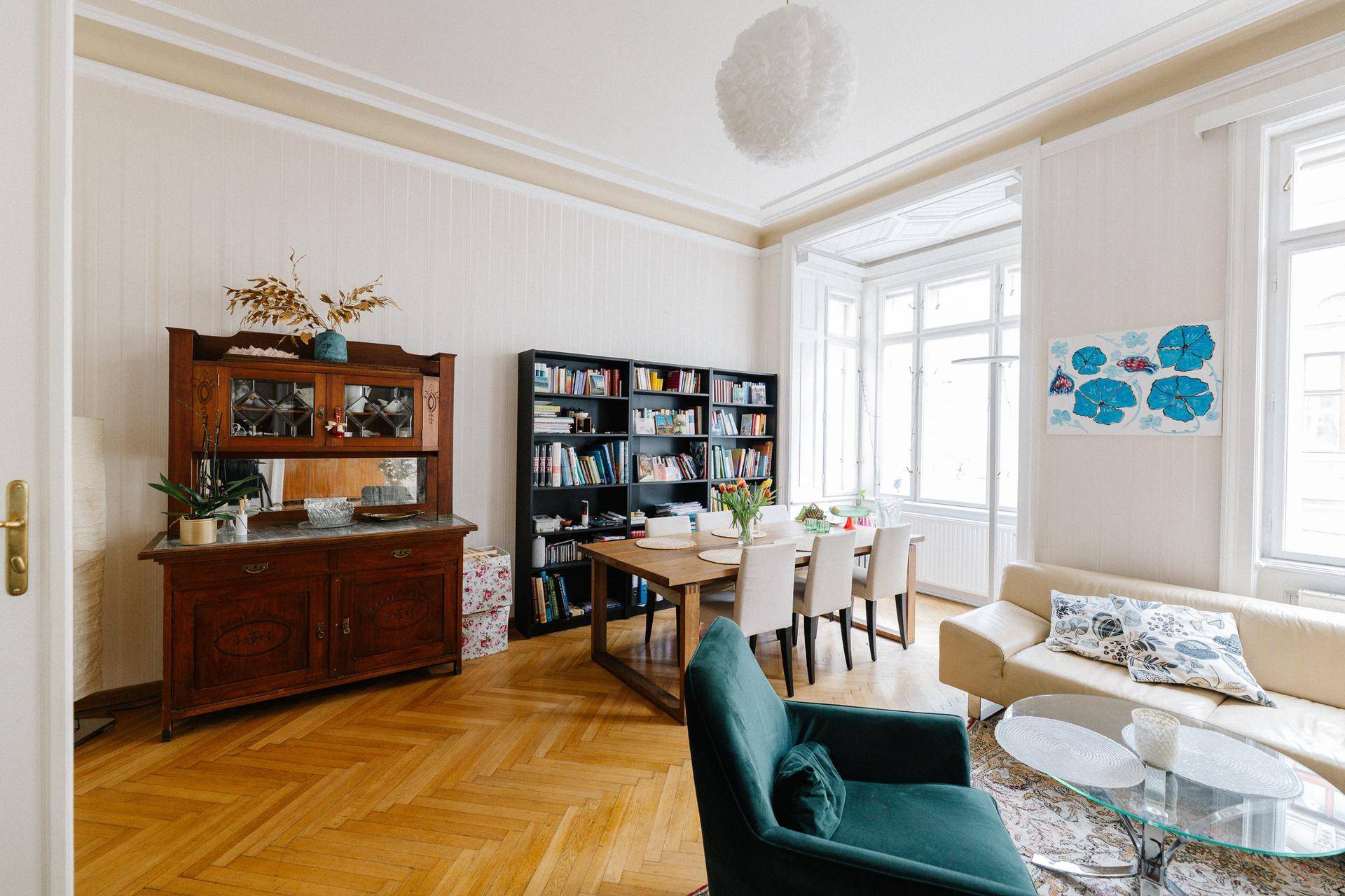 Stilvoller Wohn-Essbereich mit Parkettboden, Bücherregal und klassischem Sideboard.