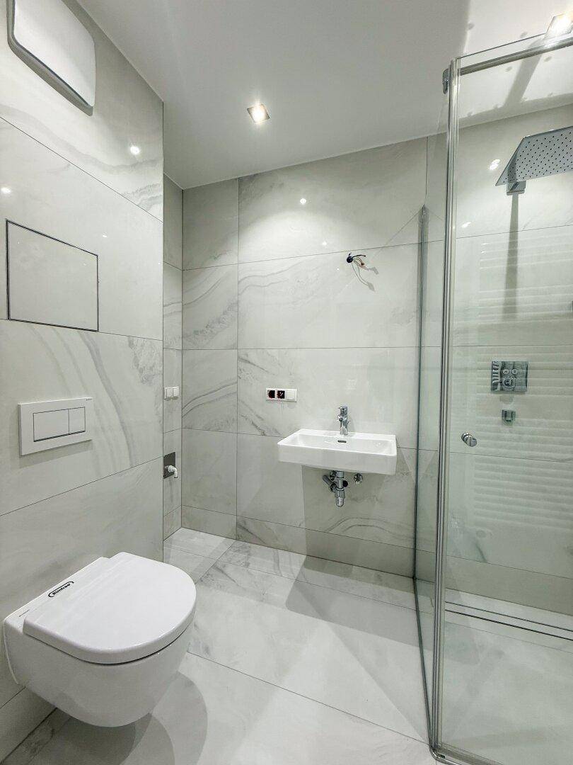 Modernes Badezimmer mit begehbarer Dusche, wandhängendem WC und eleganten Fliesen.