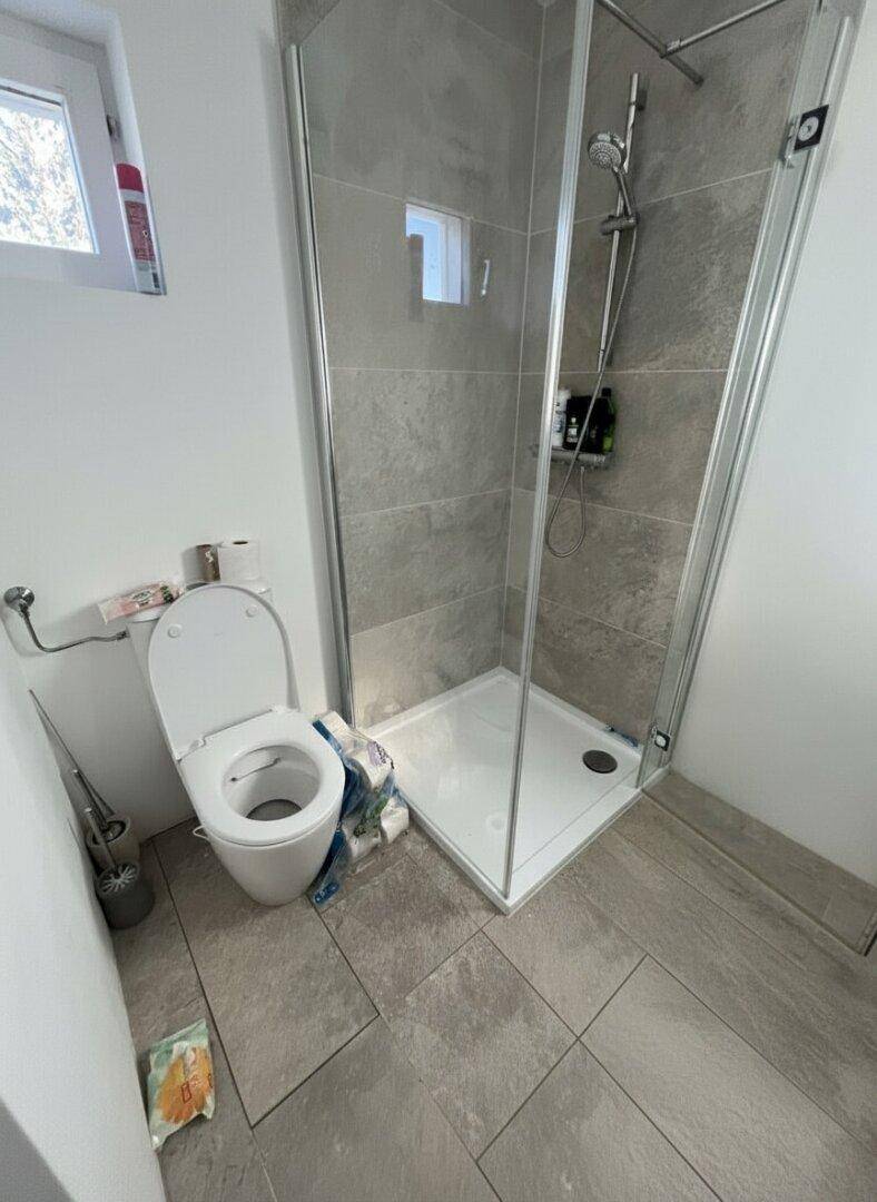 Helles Badezimmer mit Duschkabine und wandmontierter Toilette.