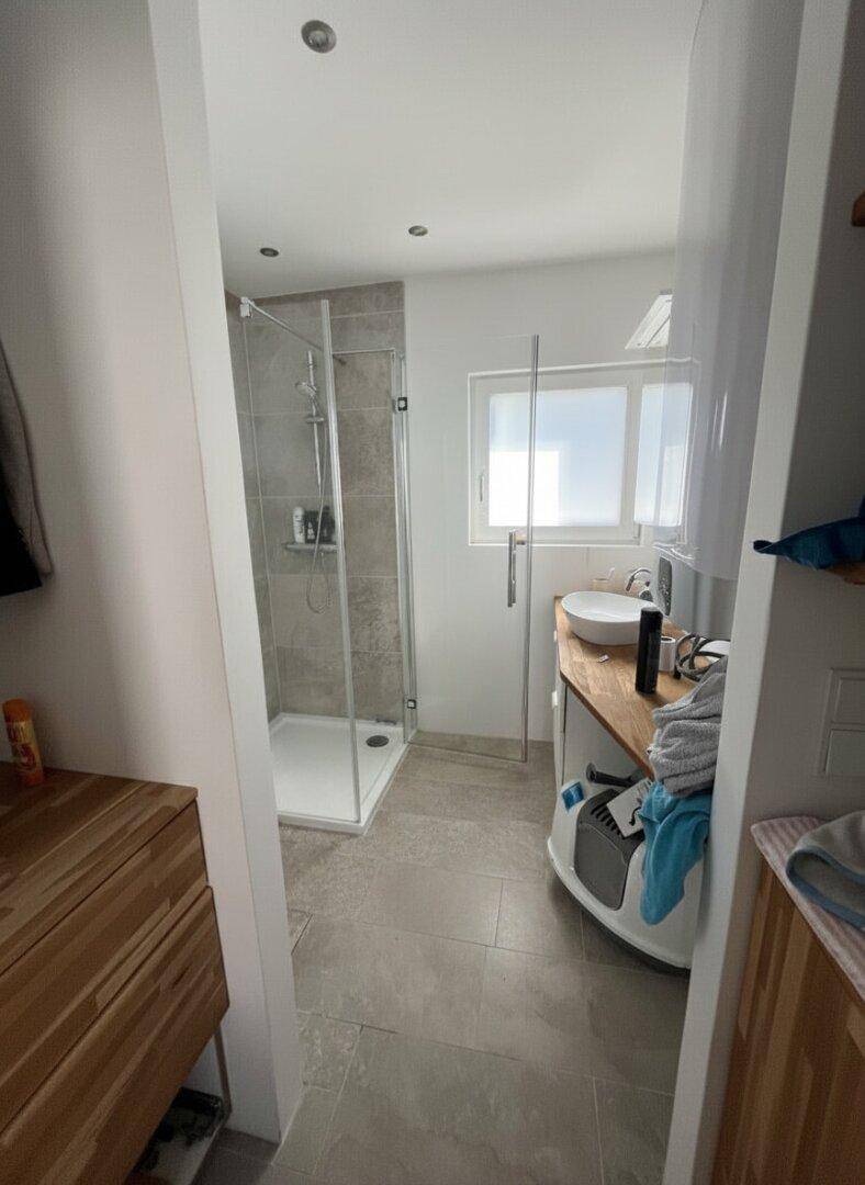 Modernes Badezimmer mit begehbarer Dusche, Holzwaschtisch und Fenster.