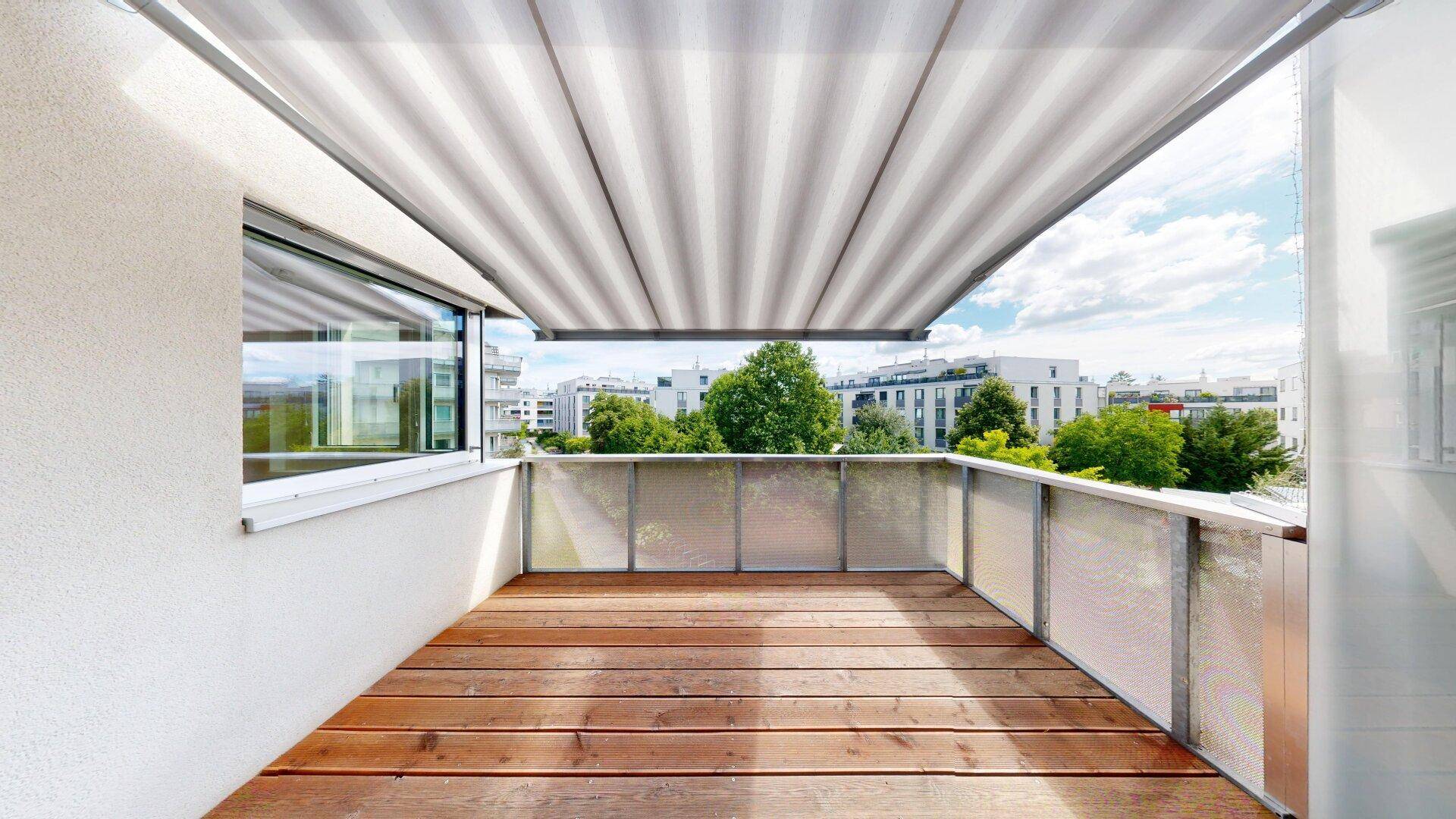 Geräumiger Balkon mit Holzboden und ausziehbarer Markise, bietet einen schönen Ausblick.