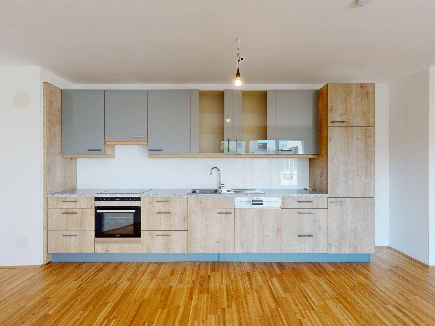 Moderne Einbauküche mit hellen Holzfronten, grauen Oberschränken und integrierten Geräten.