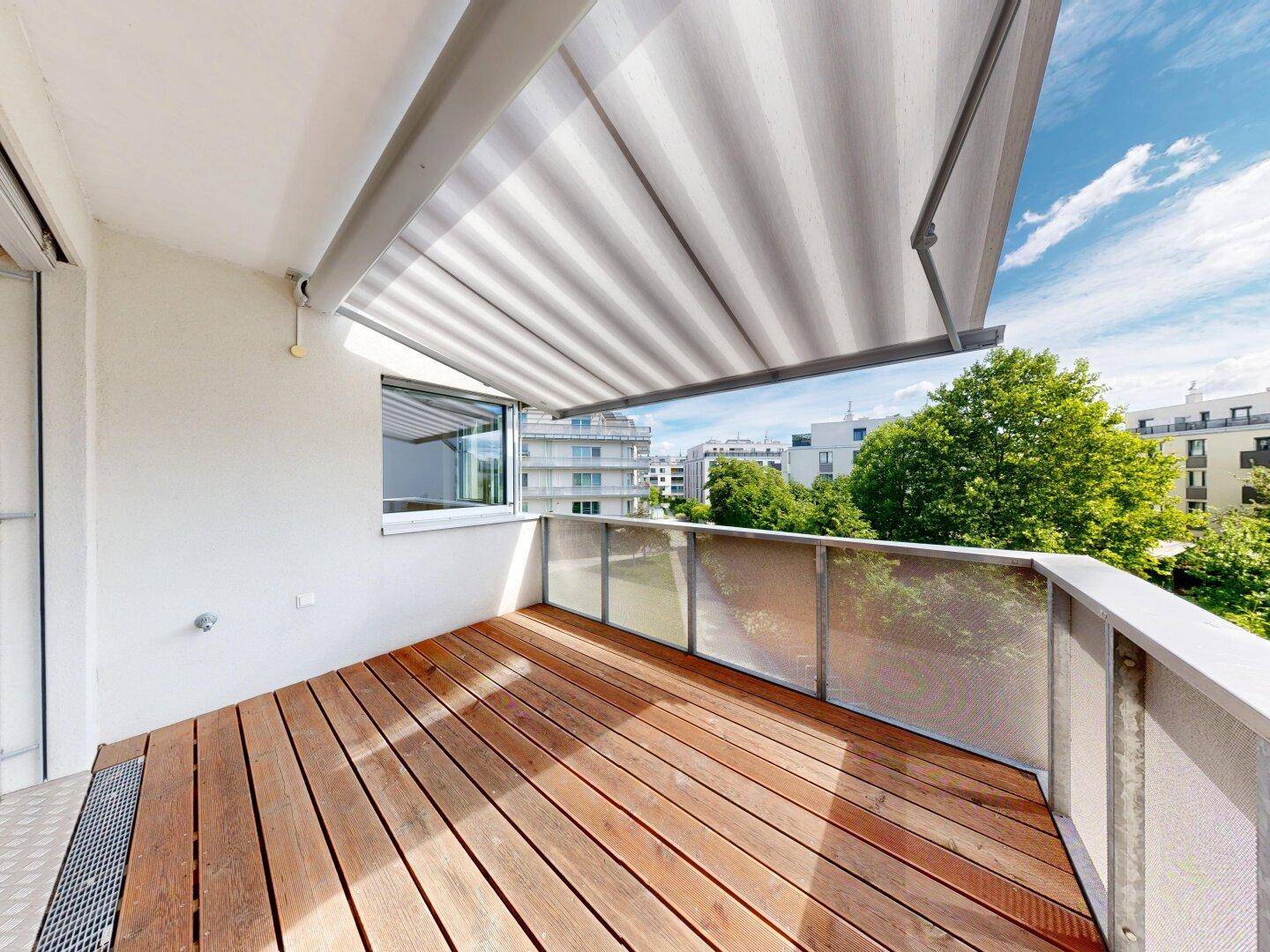 Geräumiger Balkon mit Holzboden und ausziehbarer Markise, bietet einen schönen Ausblick.