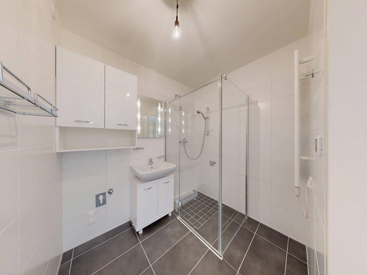 Modernes Badezimmer mit weißen Fliesen, ebenerdiger Dusche und beheiztem Handtuchhalter.