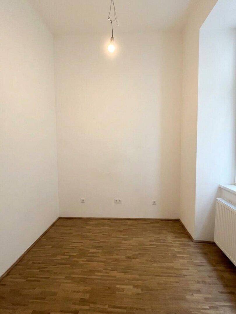 Heller, leerer Raum mit Parkettboden und einem Fenster, bereit zur individuellen Gestaltung.