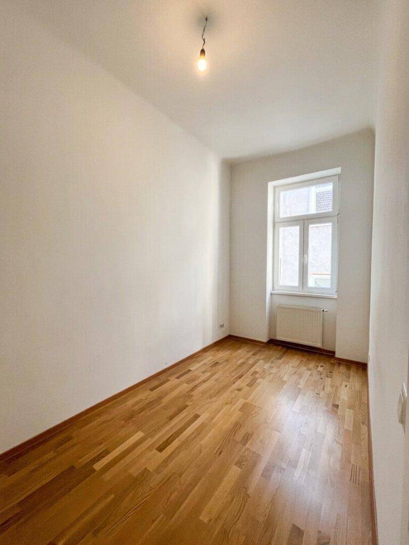 Leerer Raum mit Parkettboden und einem Fenster, bereit zur individuellen Gestaltung.