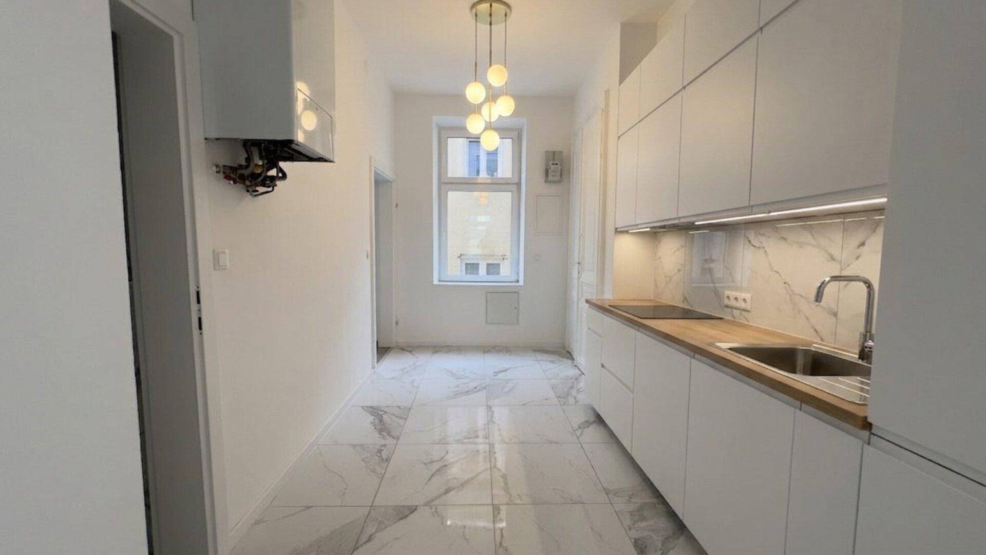 Moderne, helle Küche mit weißen Schränken, Holz-Arbeitsplatte und Marmorfliesenboden.