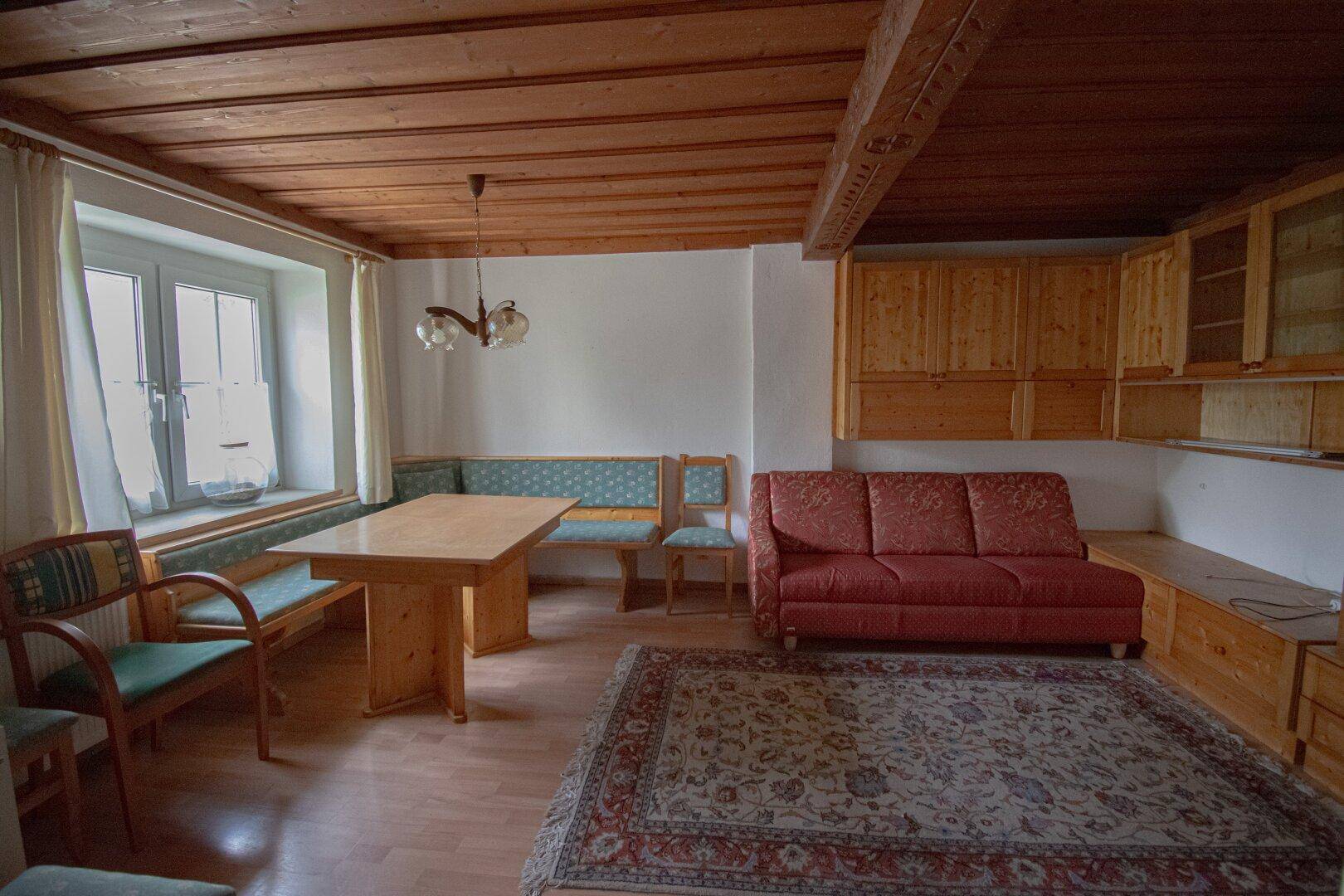 Geräumiger Wohn- und Essbereich mit Holzbalkendecke, traditionellen Möbeln und Teppich.