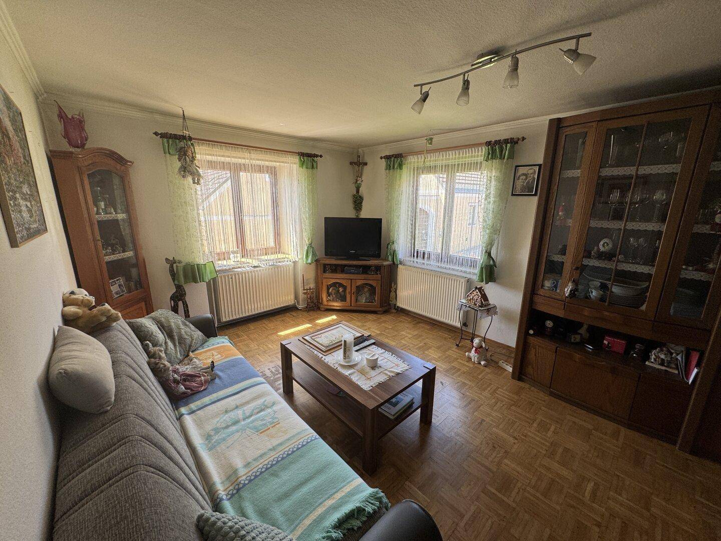 Helles Wohnzimmer mit bequemer Couch, Holzmöbeln und klassischem Parkettboden.