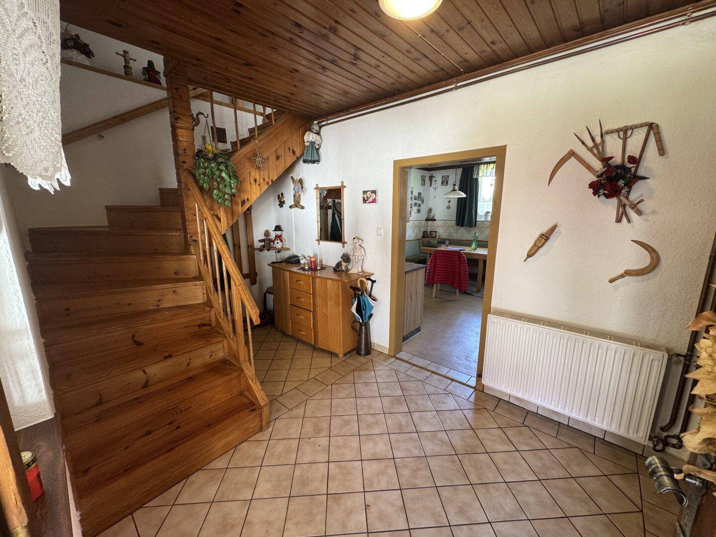 Gemütlicher Flur mit Holztreppe, Fliesenboden und traditioneller Dekoration.
