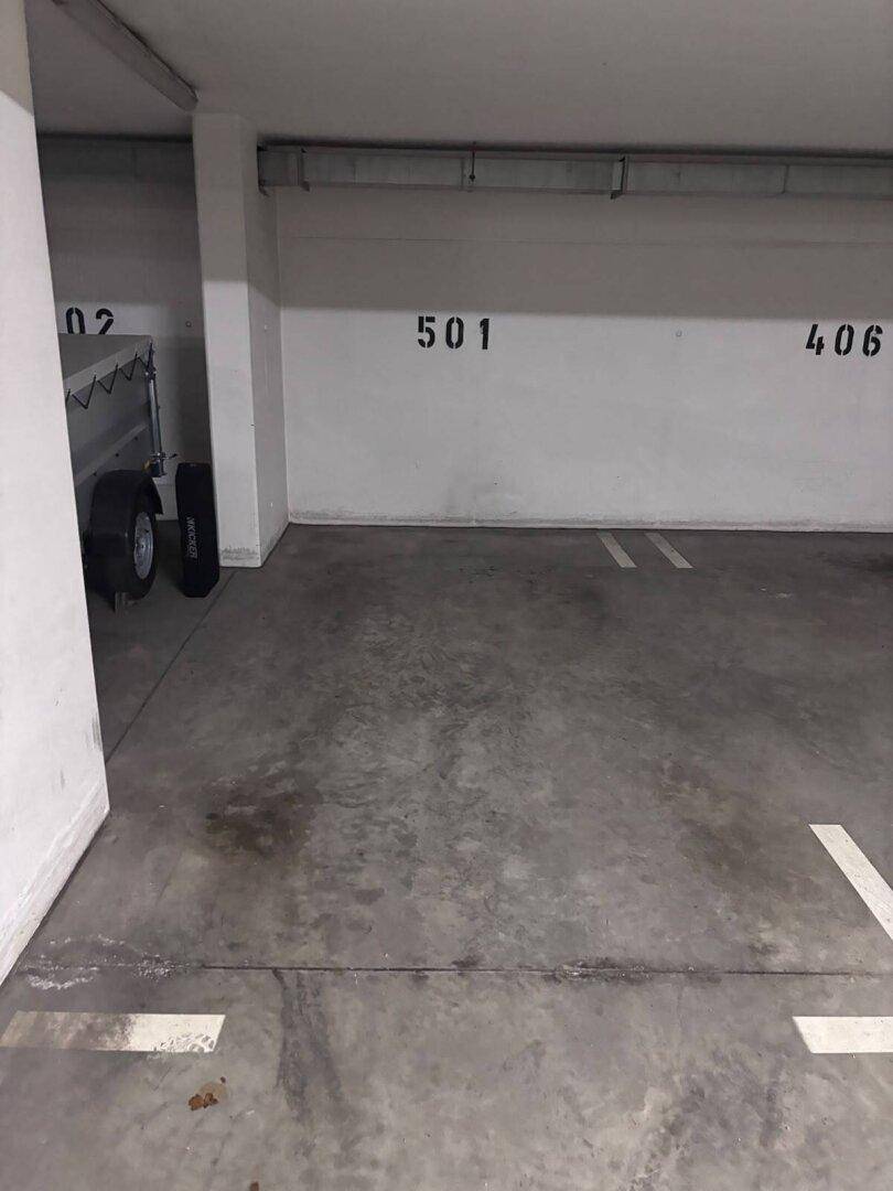 Tiefgaragenstellplatz mit Betonboden und nummerierten Parkplätzen in einem Mehrfamilienhaus.