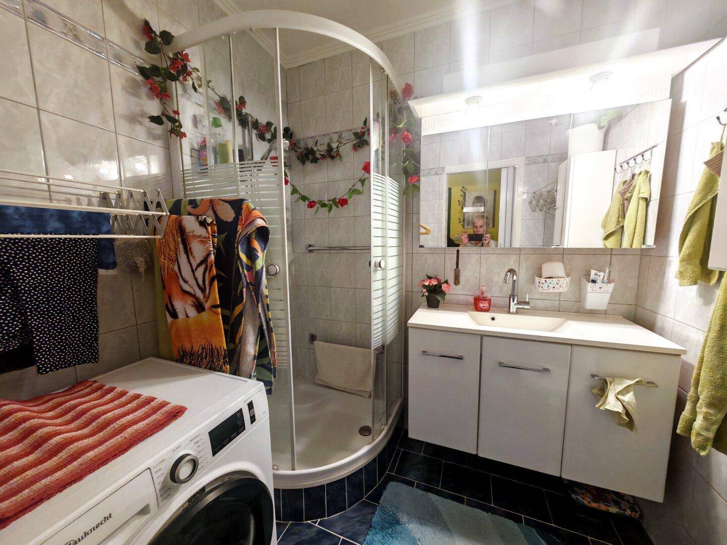 Modernes Badezimmer mit Duschkabine, Waschbeckenunterschrank und integrierter Waschmaschine.