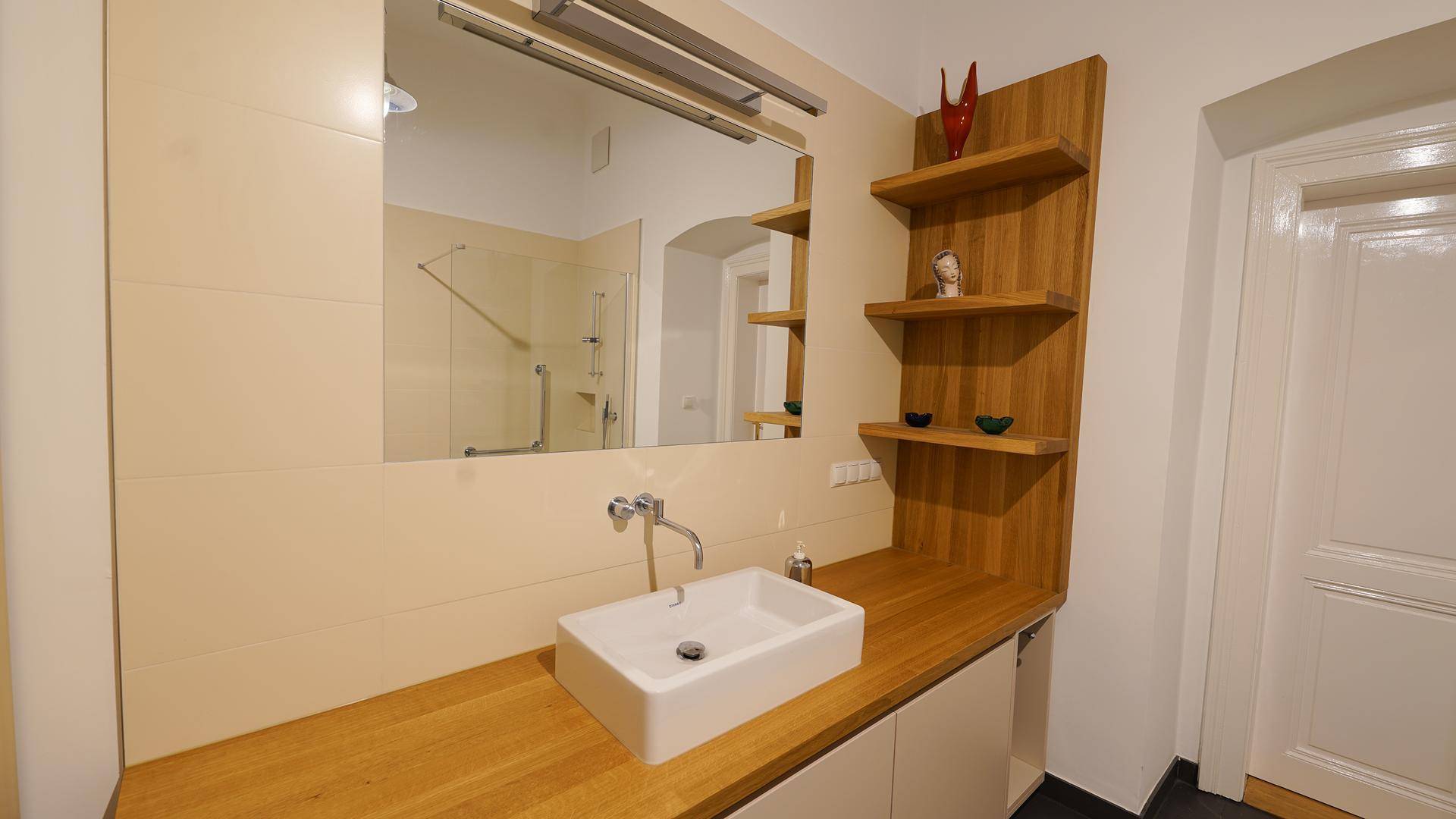 Stilvolles Badezimmer mit Holzwaschtisch, Aufsatzwaschbecken, großem Spiegel und dekorativen Regalen.