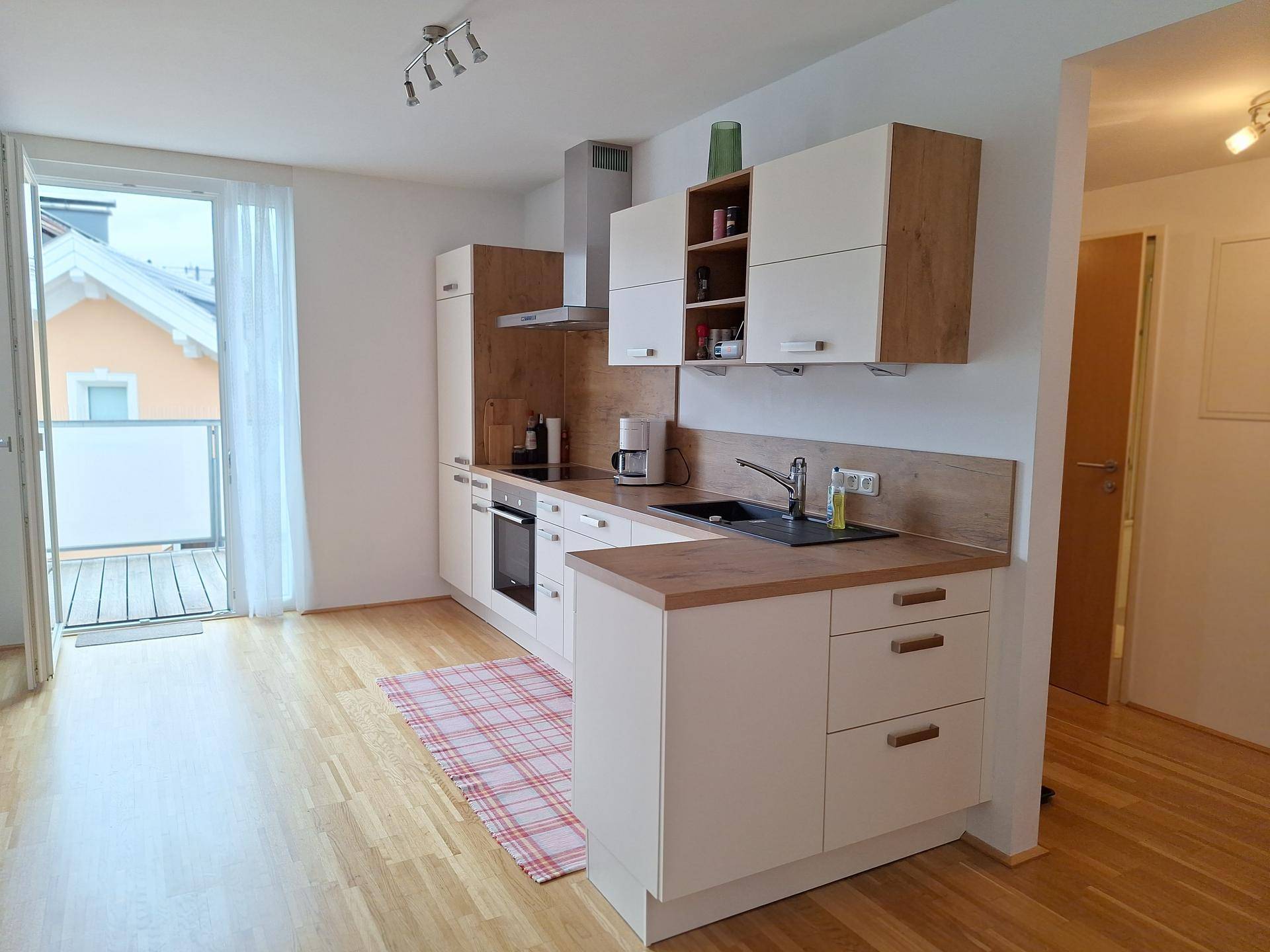 Helle Küche mit Holzarbeitsplatten und direktem Zugang zu einem sonnigen Balkon, der den Raum erhellt.