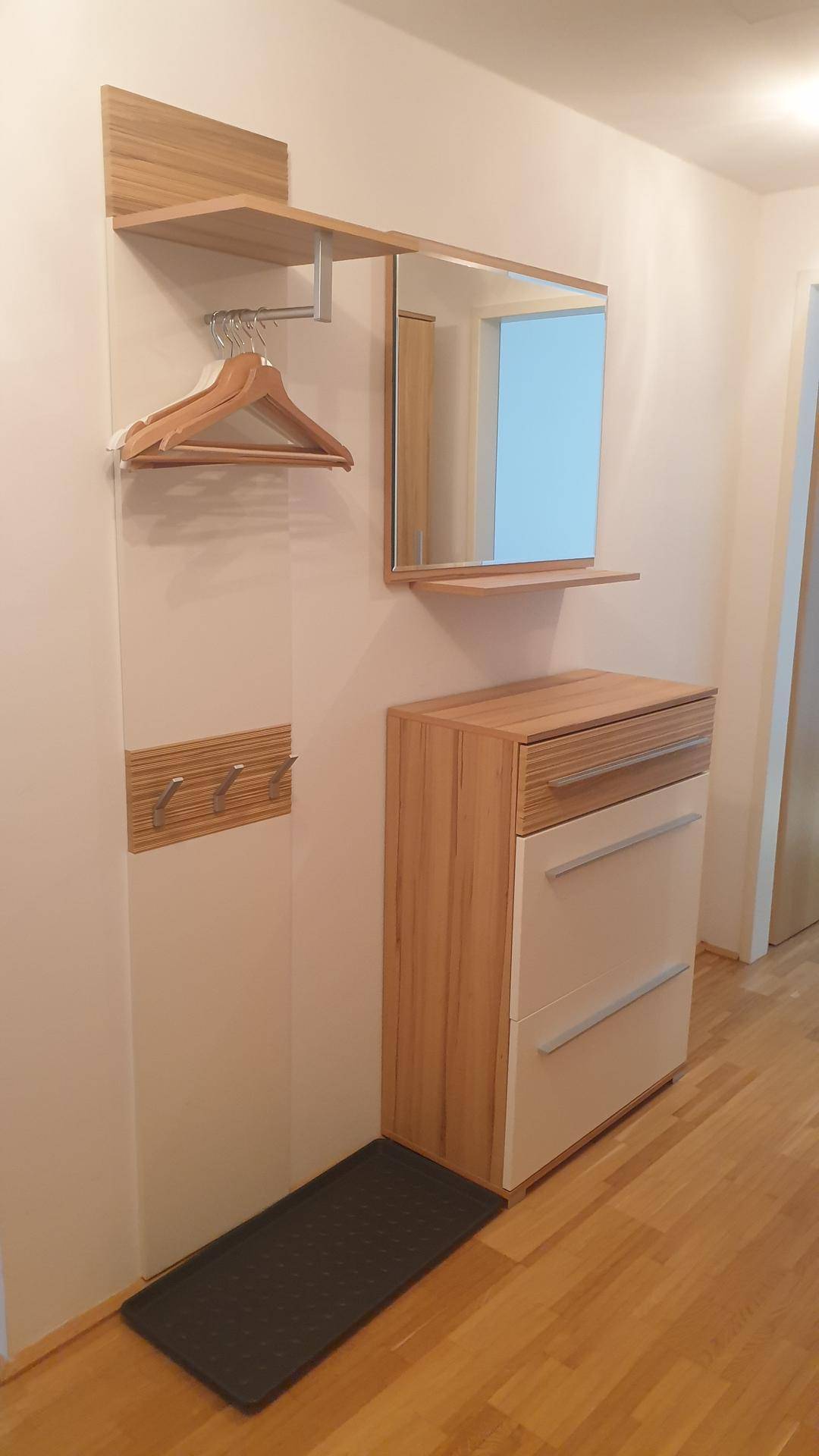 Heller Flur mit Garderobe, Spiegel und einer Kommode aus hellem Holz für zusätzlichen Stauraum.