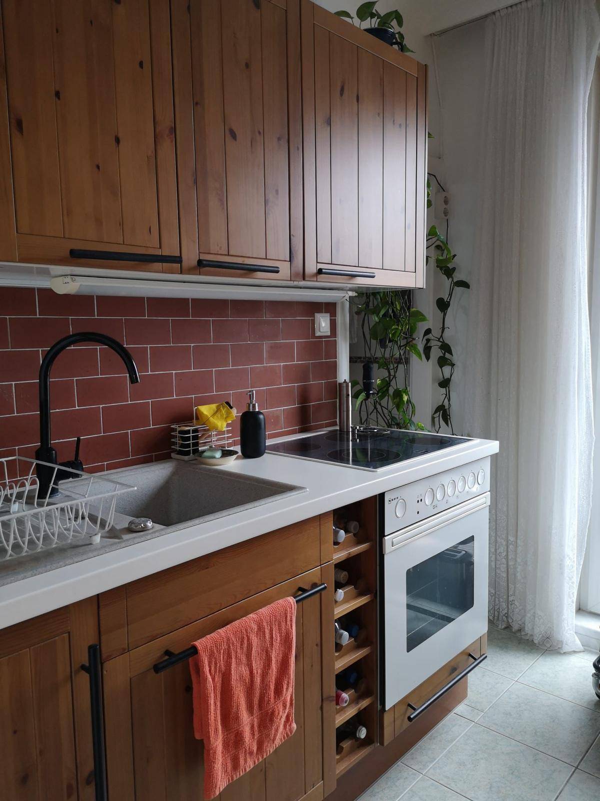 Funktionale Küche mit Holzelementen, rotem Fliesenspiegel und integriertem Herd mit Backofen.