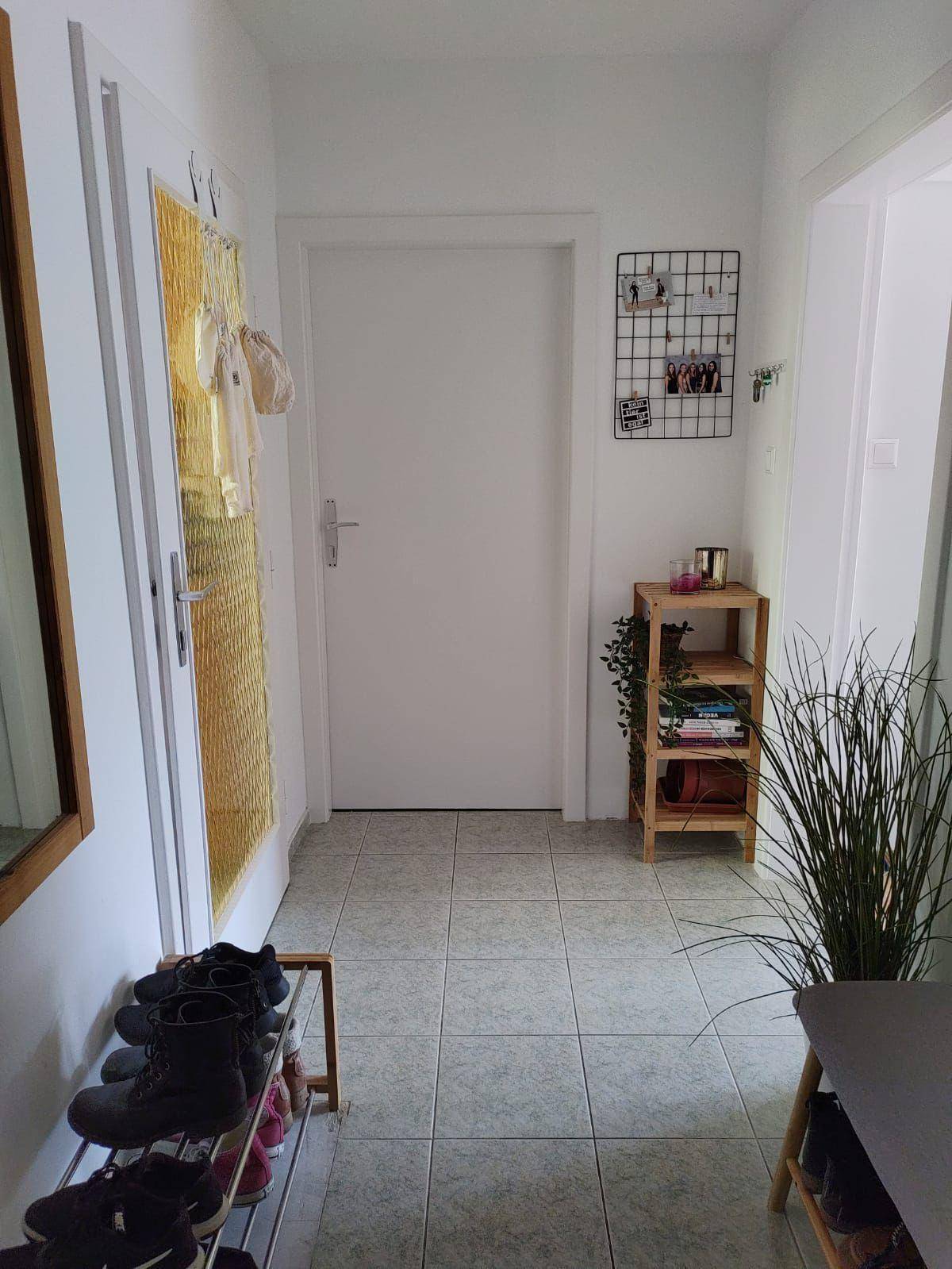Heller Flur mit Fliesenboden, Schuhregal und einem großen Wandspiegel.
