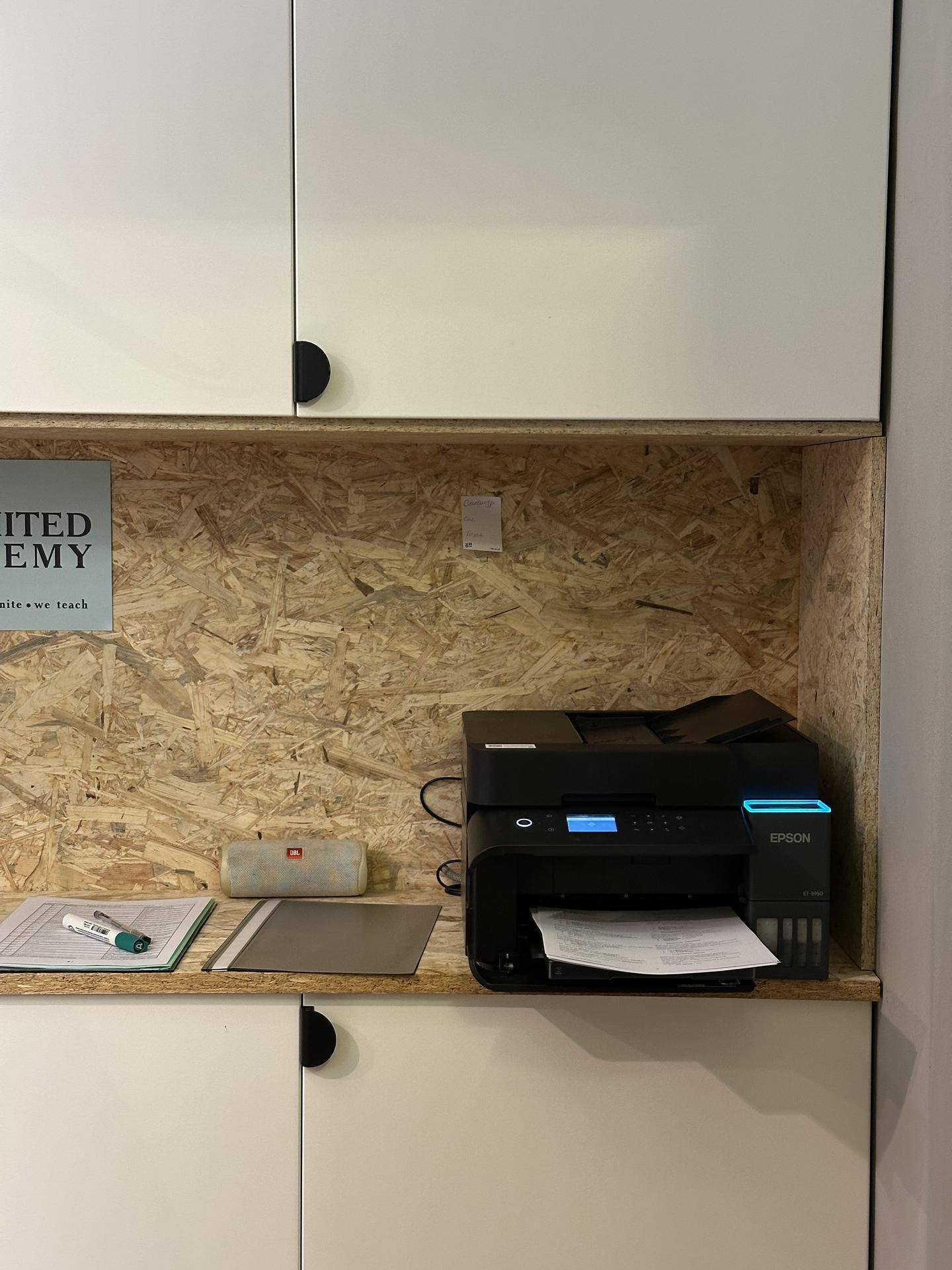 Detailansicht eines Druckers auf einem Regal mit OSB-Plattenhintergrund in einem Büroschrank.