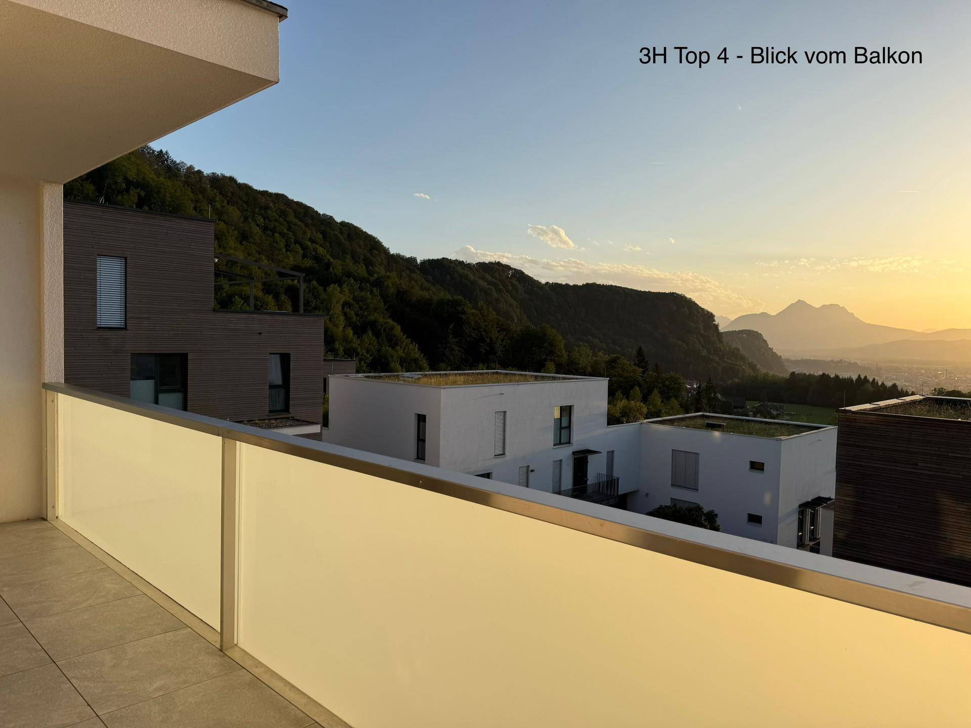Heller Balkon mit Fliesenboden und Glasbrüstung, bietet einen weiten Blick auf die Landschaft und Berge.