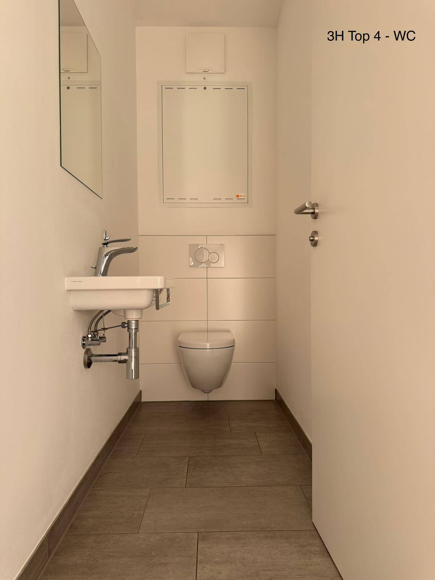 Helles Gäste-WC mit wandhängender Toilette, kleinem Waschbecken und modernen Fliesen.