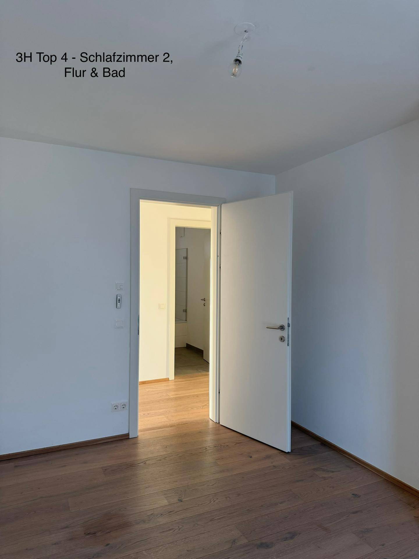 Helles Schlafzimmer mit Holzboden und Blick in einen angrenzenden Flur und weitere Räume.