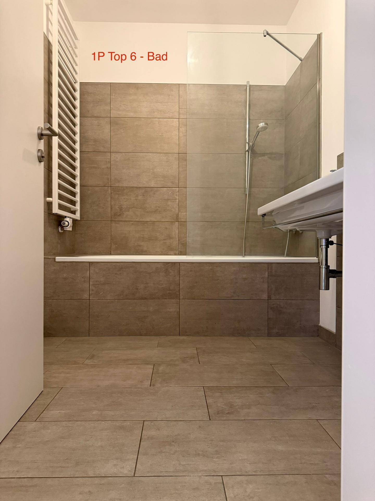 Modernes Badezimmer mit Badewanne, Duschabtrennung und praktischem beheiztem Handtuchhalter.