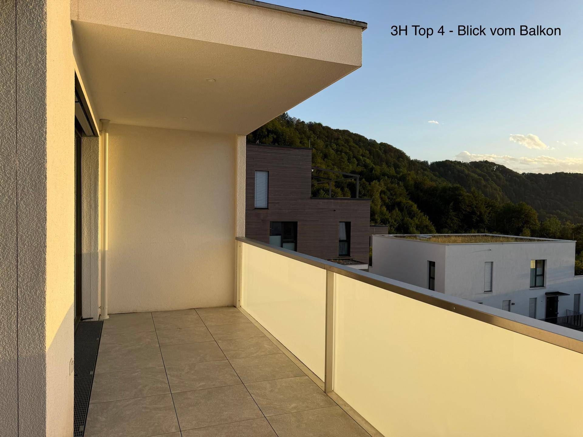 Geräumiger Balkon mit Fliesenboden und moderner Glasbrüstung, ideal für entspannte Stunden.