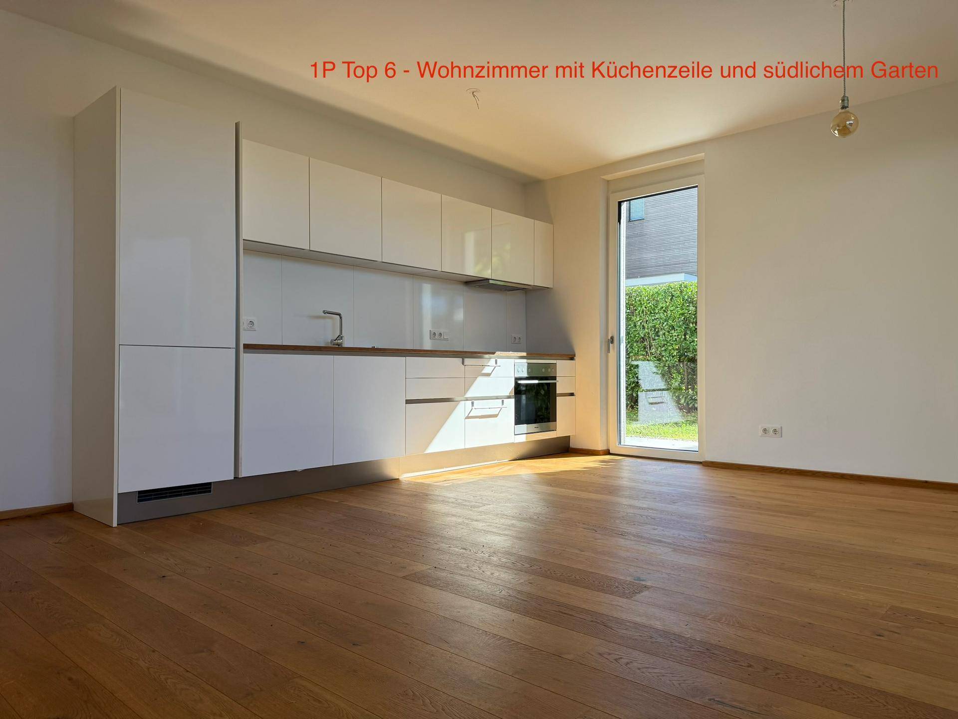 Wohnzimmer mit integrierter weißer Küchenzeile, Eichenparkett und Zugang zum südlichen Garten.