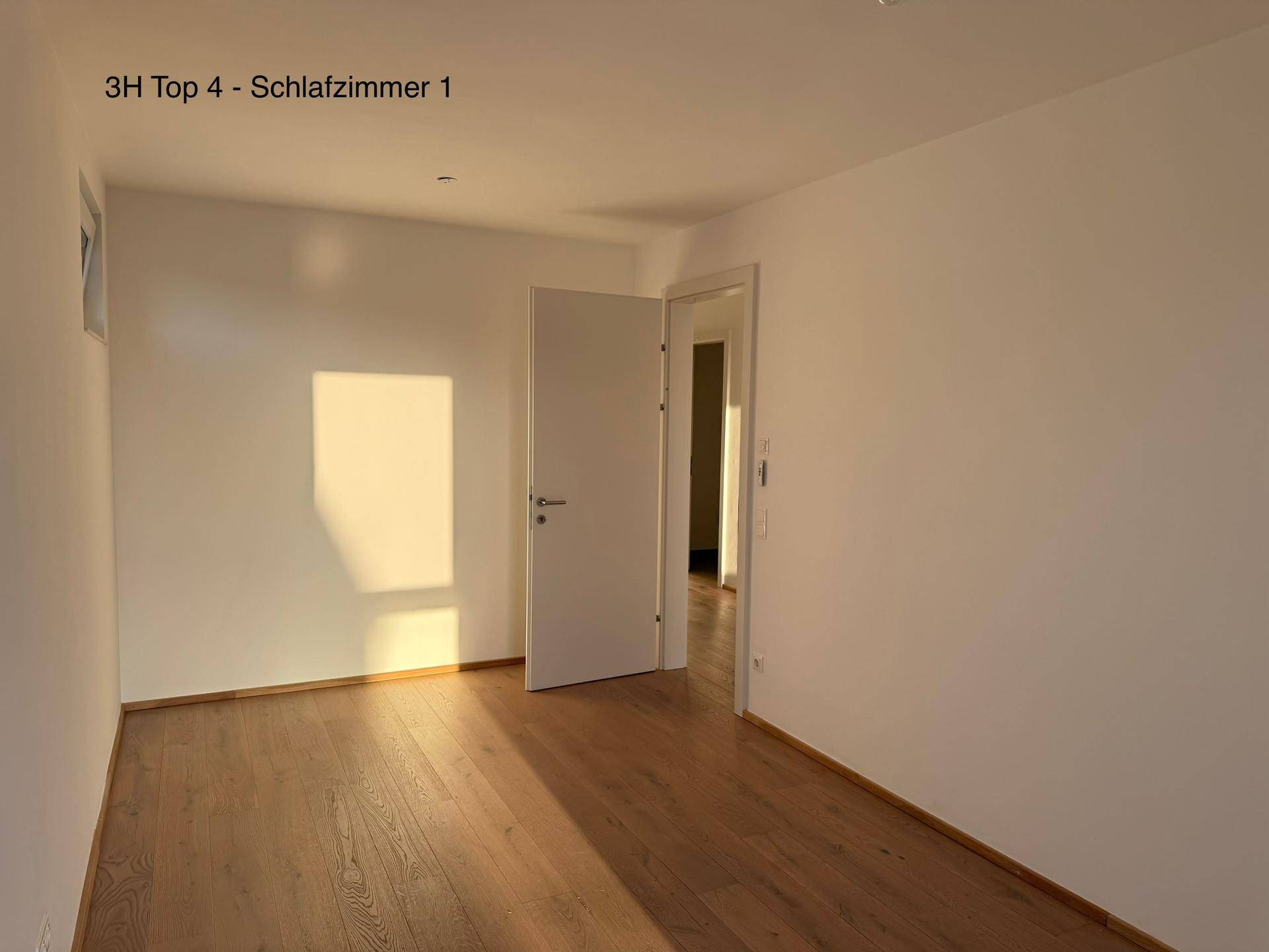 Geräumiges Schlafzimmer mit Holzboden und viel natürlichem Sonnenlicht, das den Raum erhellt.