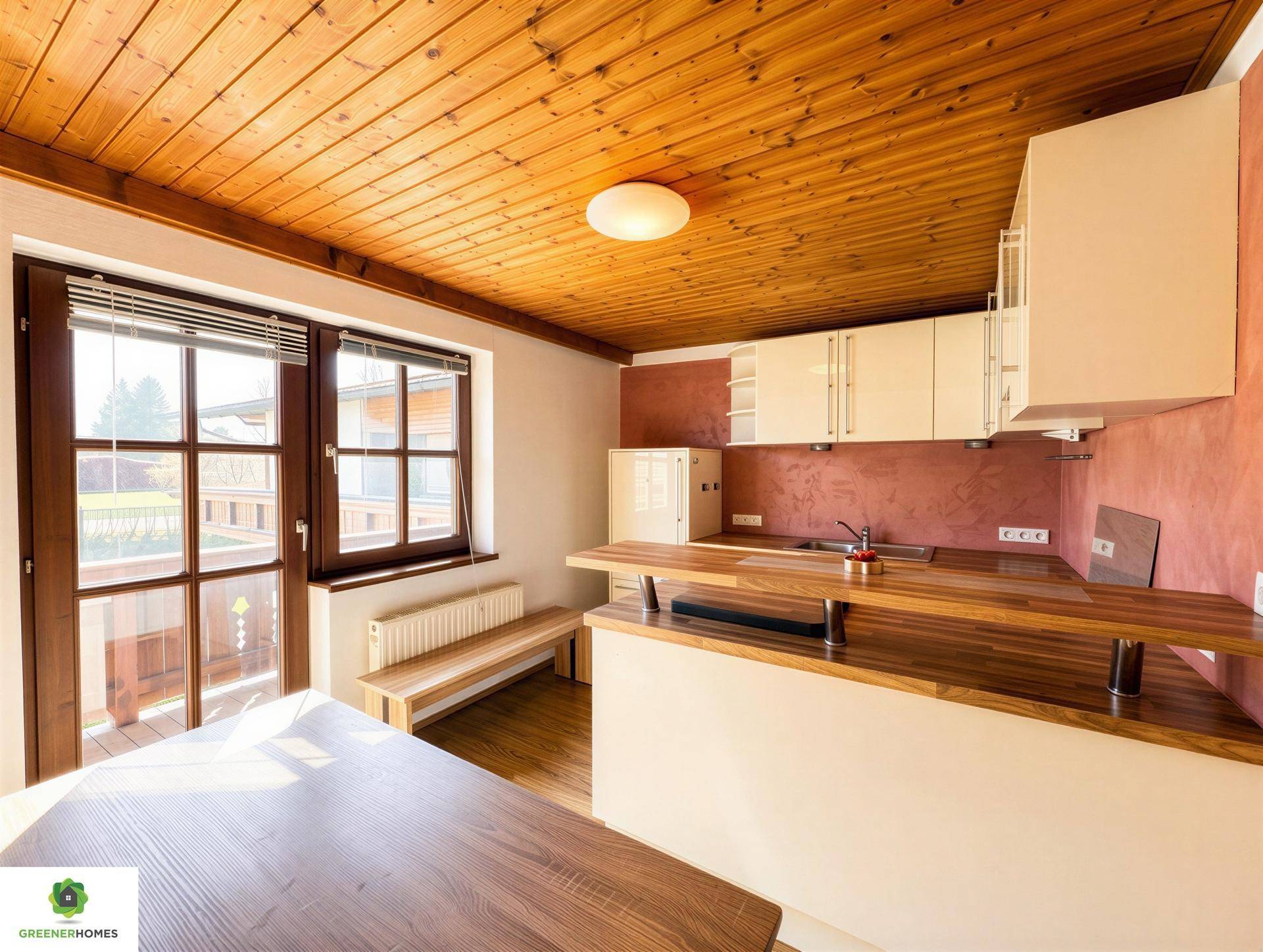 Gemütliche Küche mit Holzbalkendecke, Essbereich und Zugang zu einem Balkon.