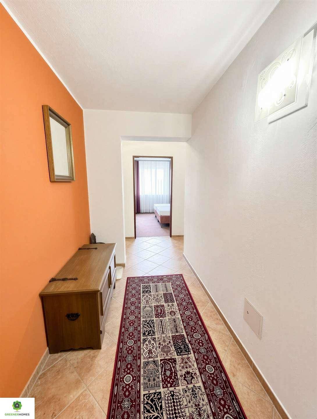 Heller Flur mit Terrakotta-Fliesenboden, einer Holztruhe und einem Spiegel an der Wand.