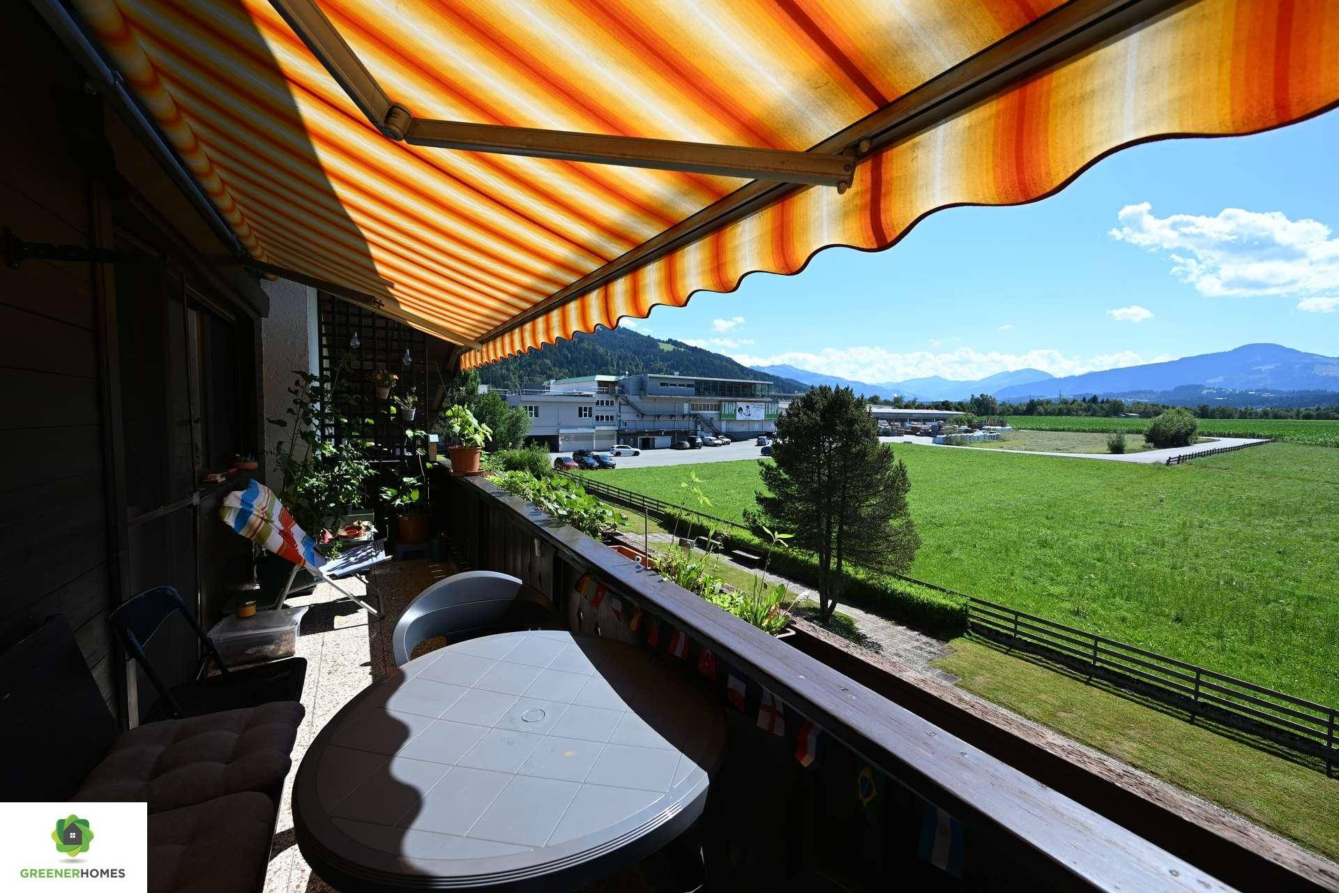 Sonniger Balkon mit Markise, Tisch und Stühlen, bietet weite Aussicht auf die Umgebung.