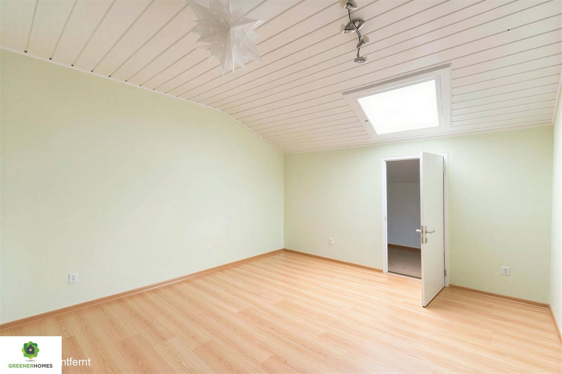 Heller Raum mit Dachschräge, Holzpaneeldecke und einem Dachfenster.